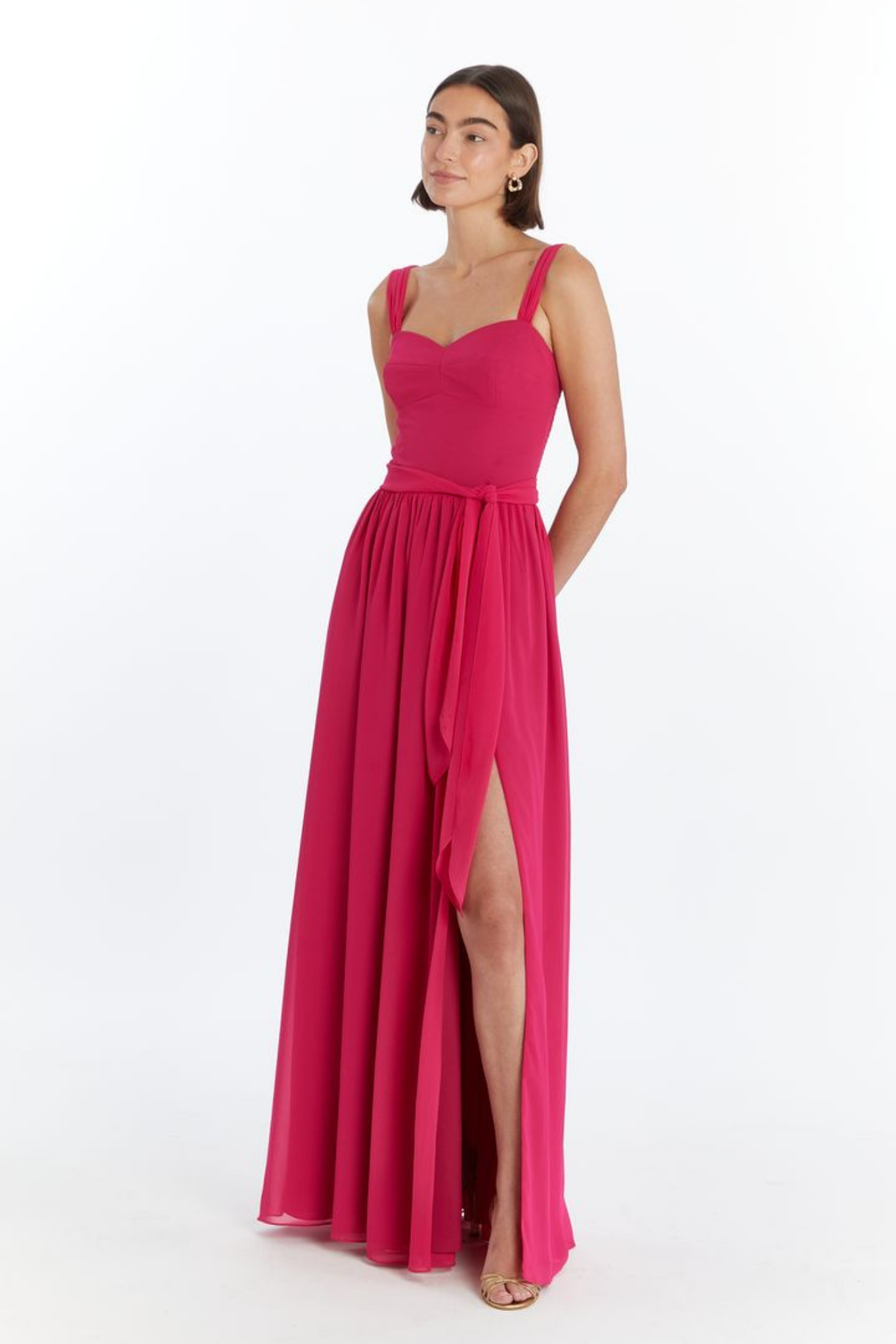 Girl in long red maxi dress with slit, side facing.