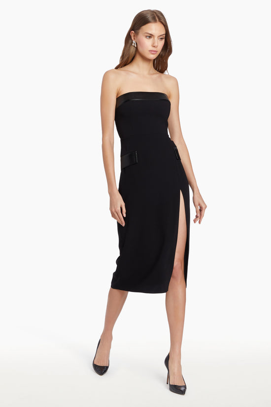 Girl in black midi dress with leather details and slit, side facing. view 2