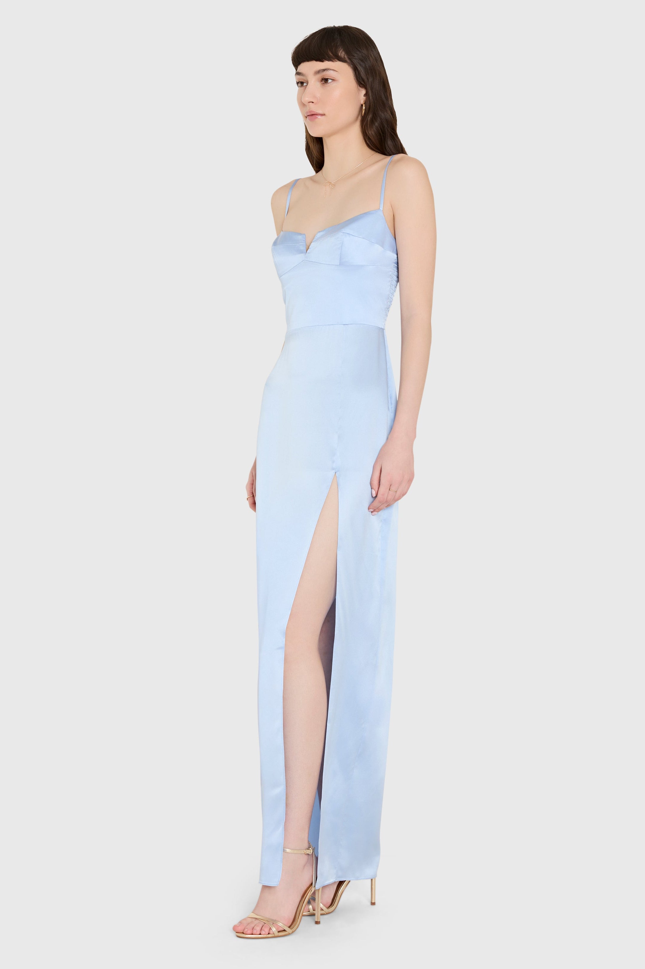 Woman wearing a light blue gown with a slit on a white background