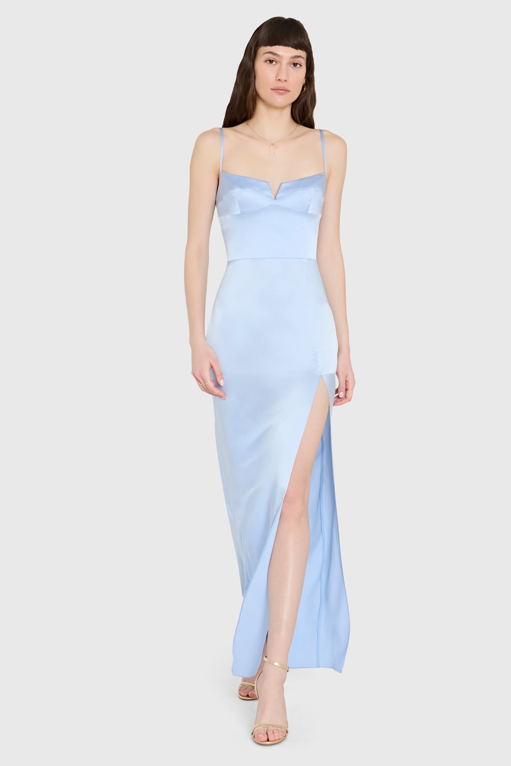 Woman wearing a light blue dress with a slit on a white background