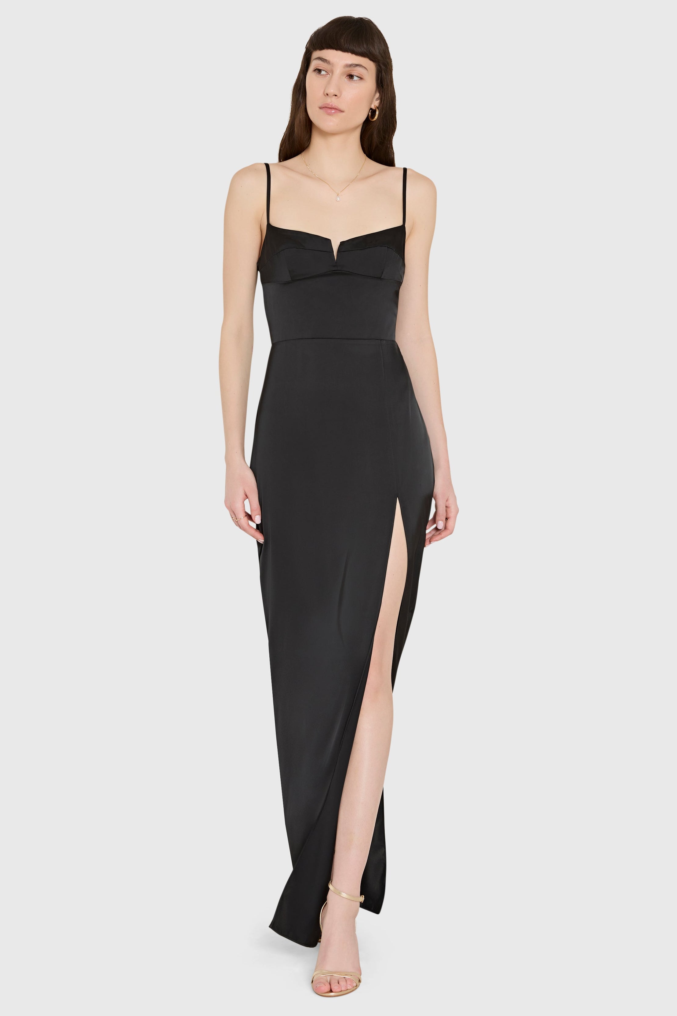 Woman wearing a black evening gown with a slit on a white background