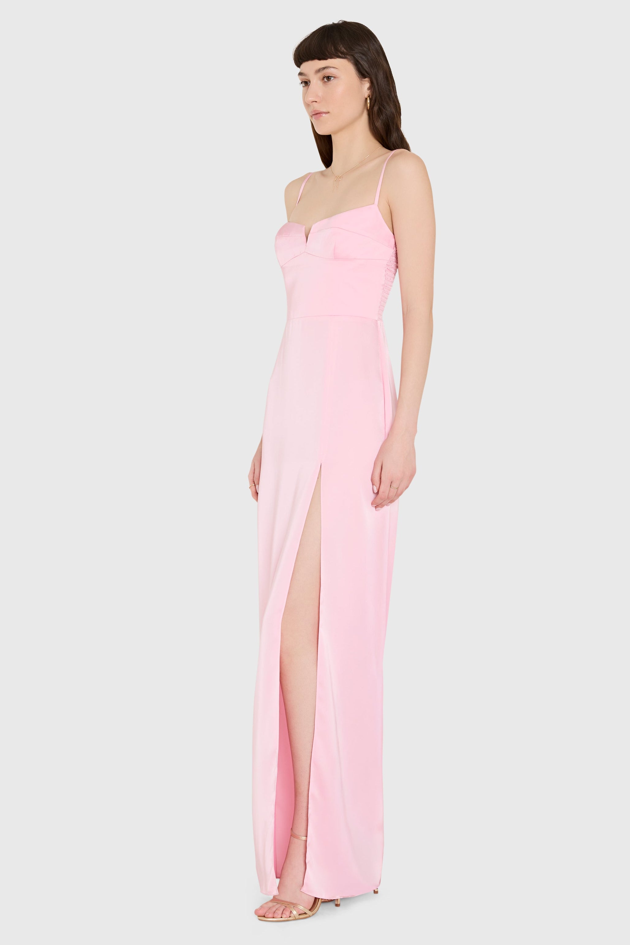 Woman wearing a pink gown with a slit on a white background