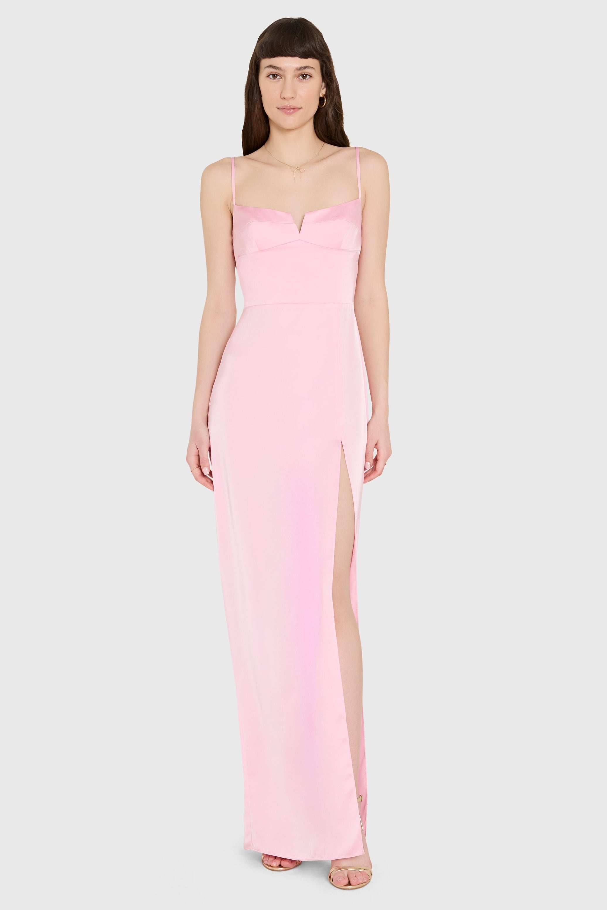 Woman wearing a pink gown with a slit on a white background
