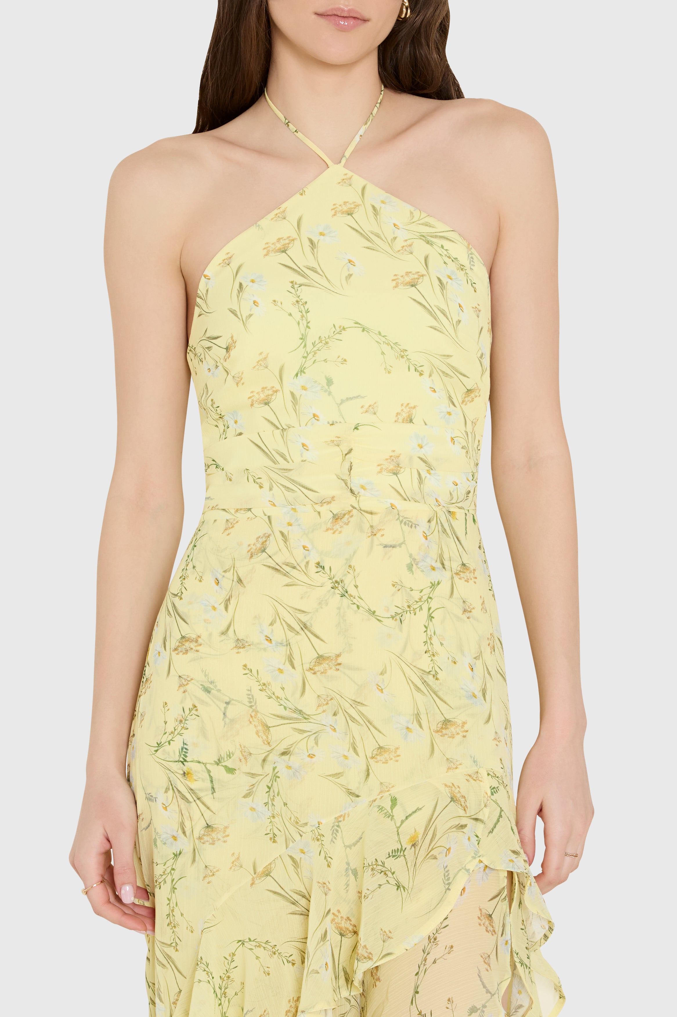 Woman wearing a yellow floral dress against a white background