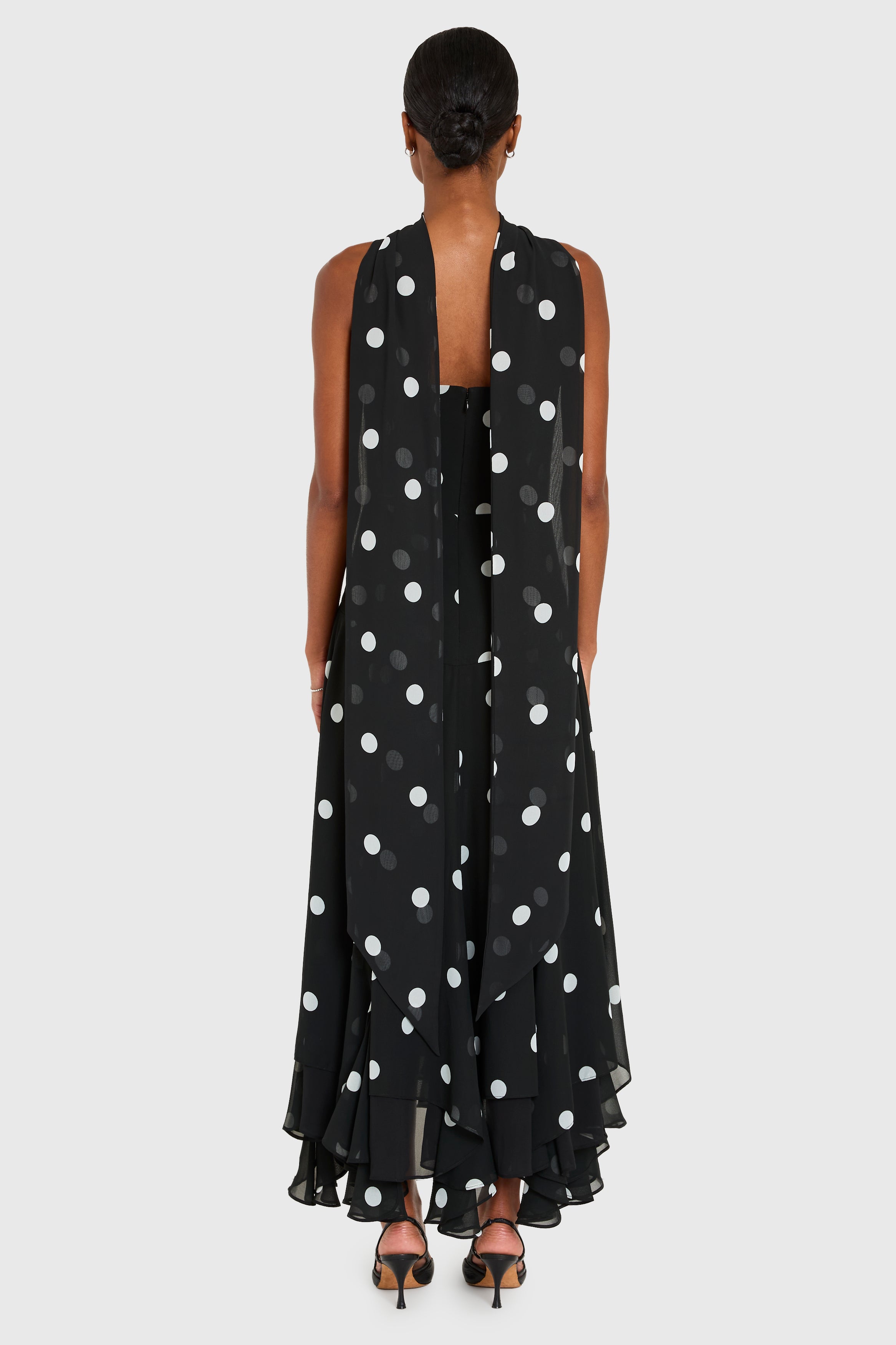 Black sleeveless dress with white polka dots on a white background