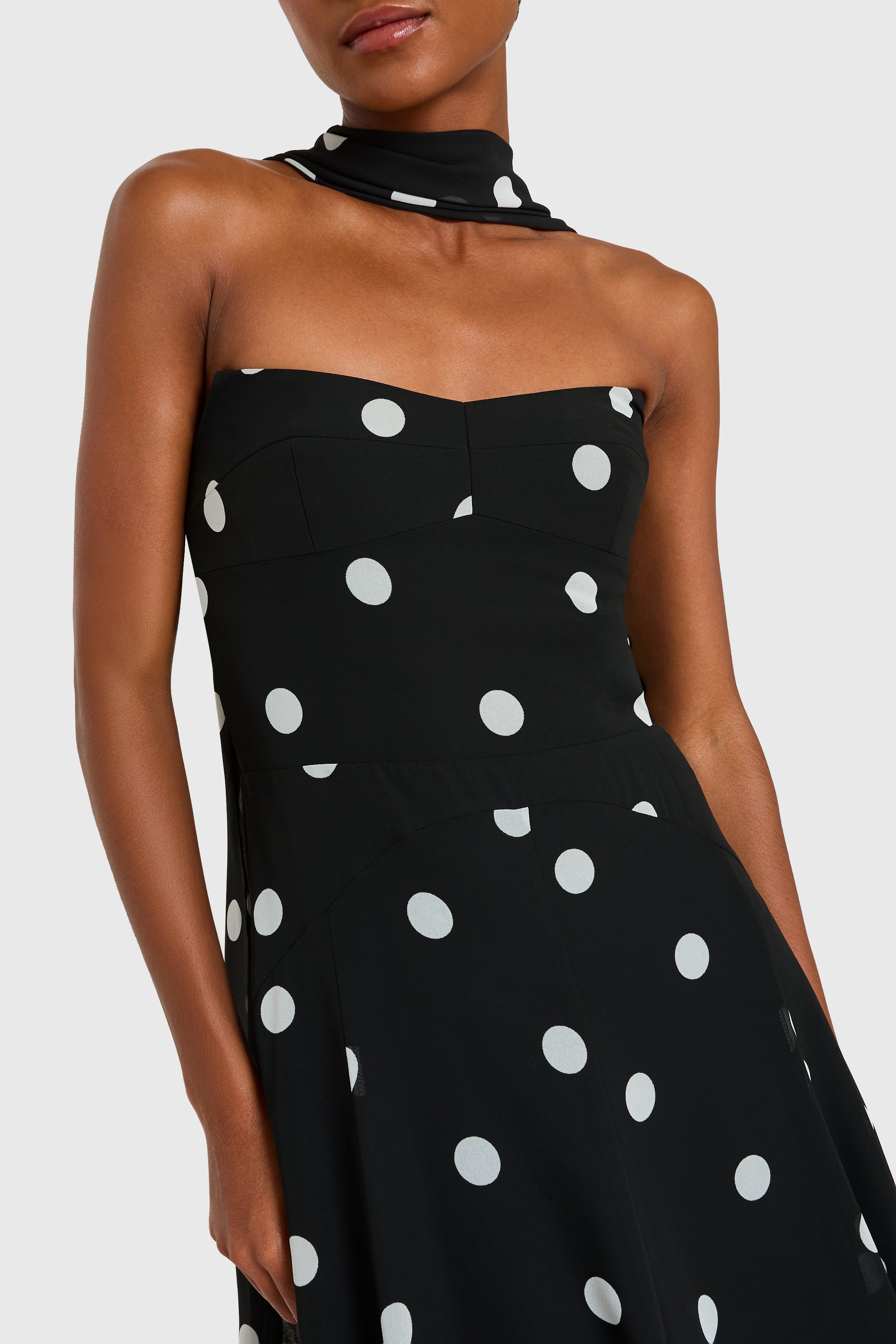 Black strapless dress with white polka dots on a white background