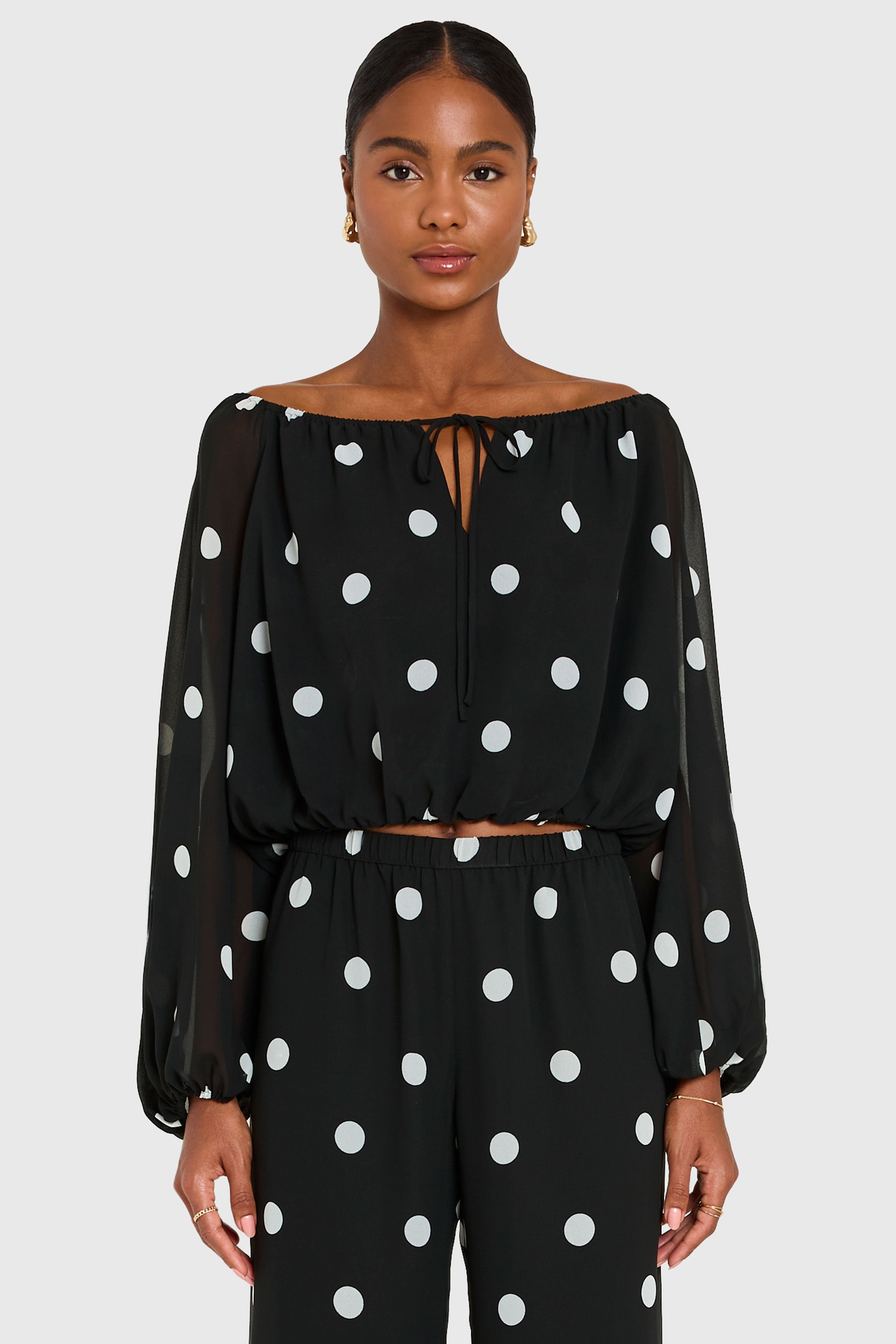Woman wearing a black polka dot outfit on a white background