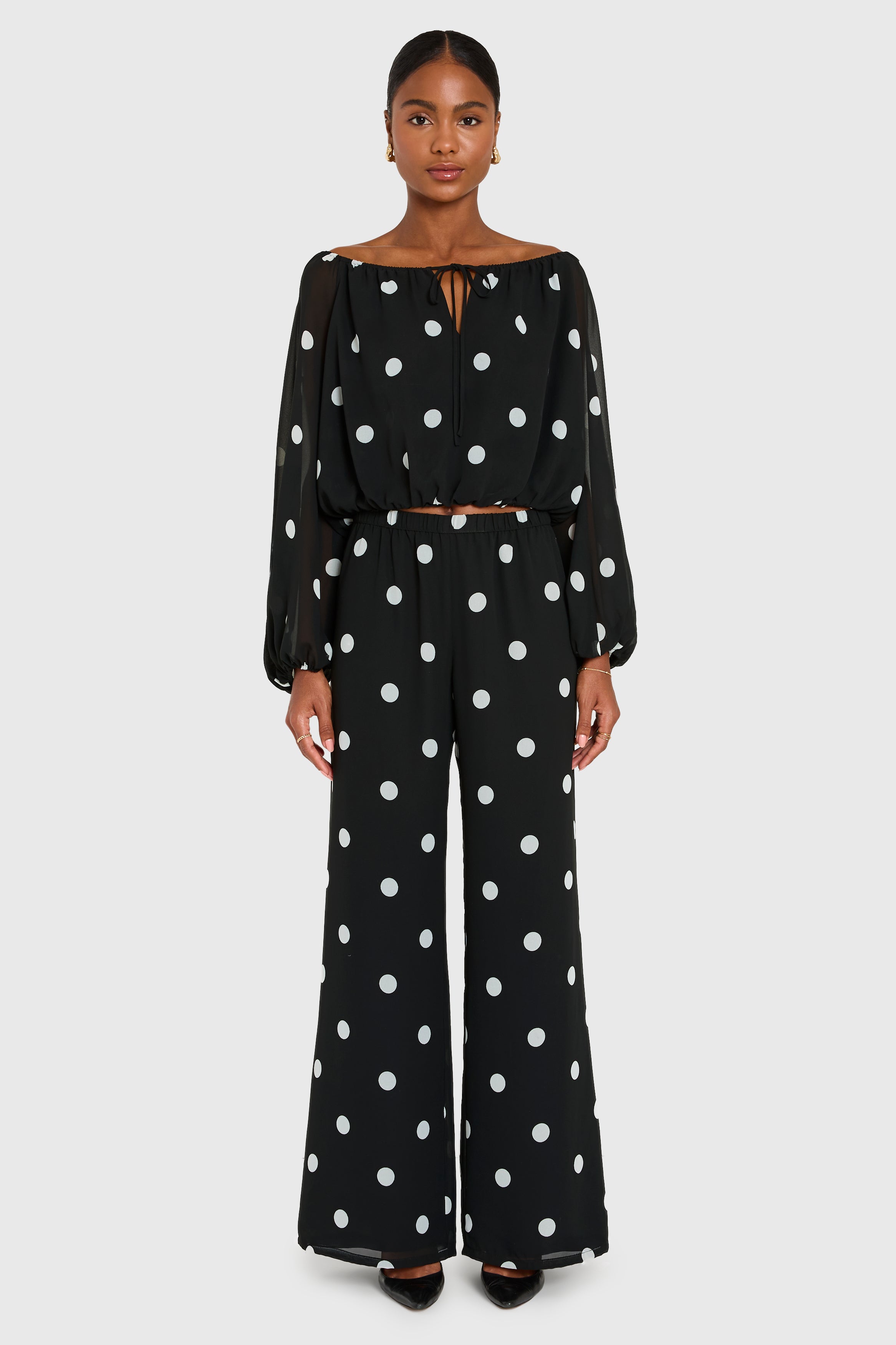 Woman wearing a black polka dot outfit on a white background