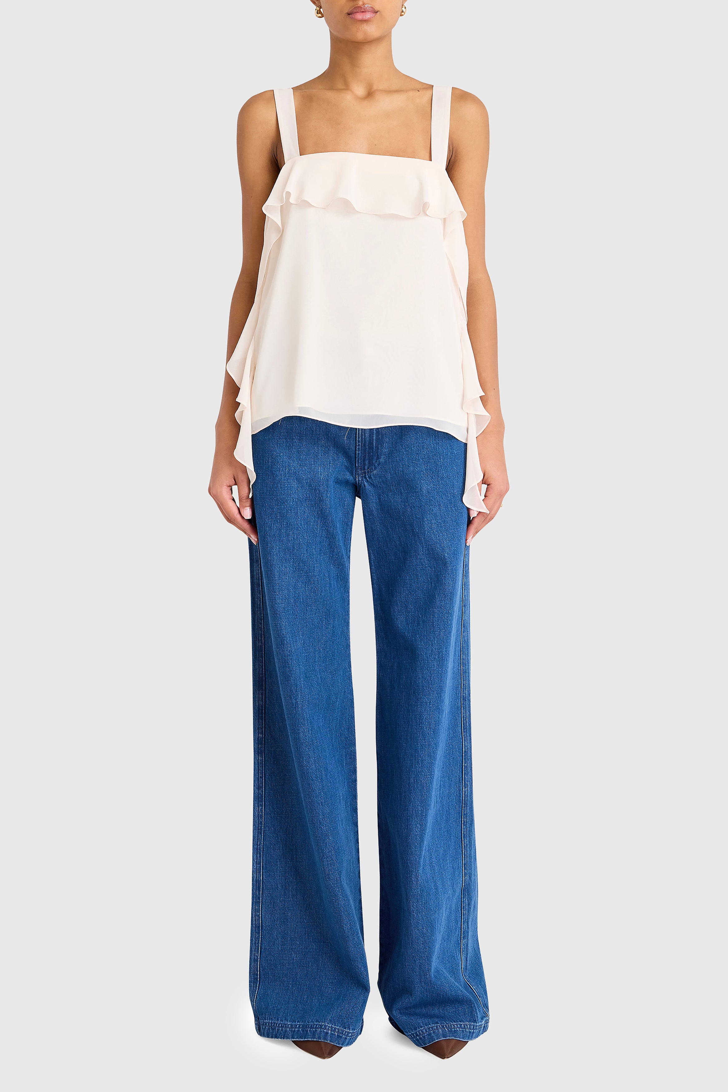 Woman wearing a white top and blue jeans on a white background