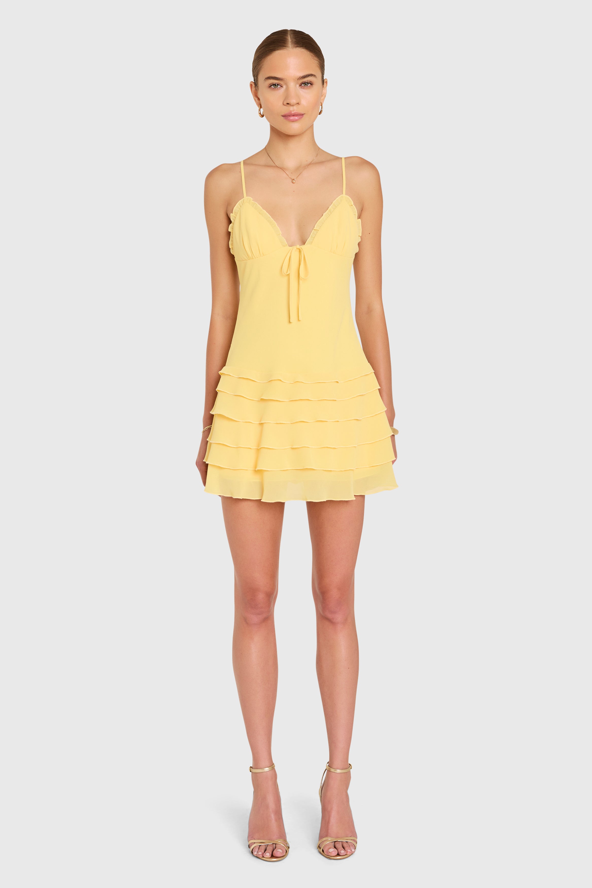 Amanda Uprichard |  Mirabelle Romper in Daffodil Yellow. Model wears a yellow mini dress against a white backgorund.