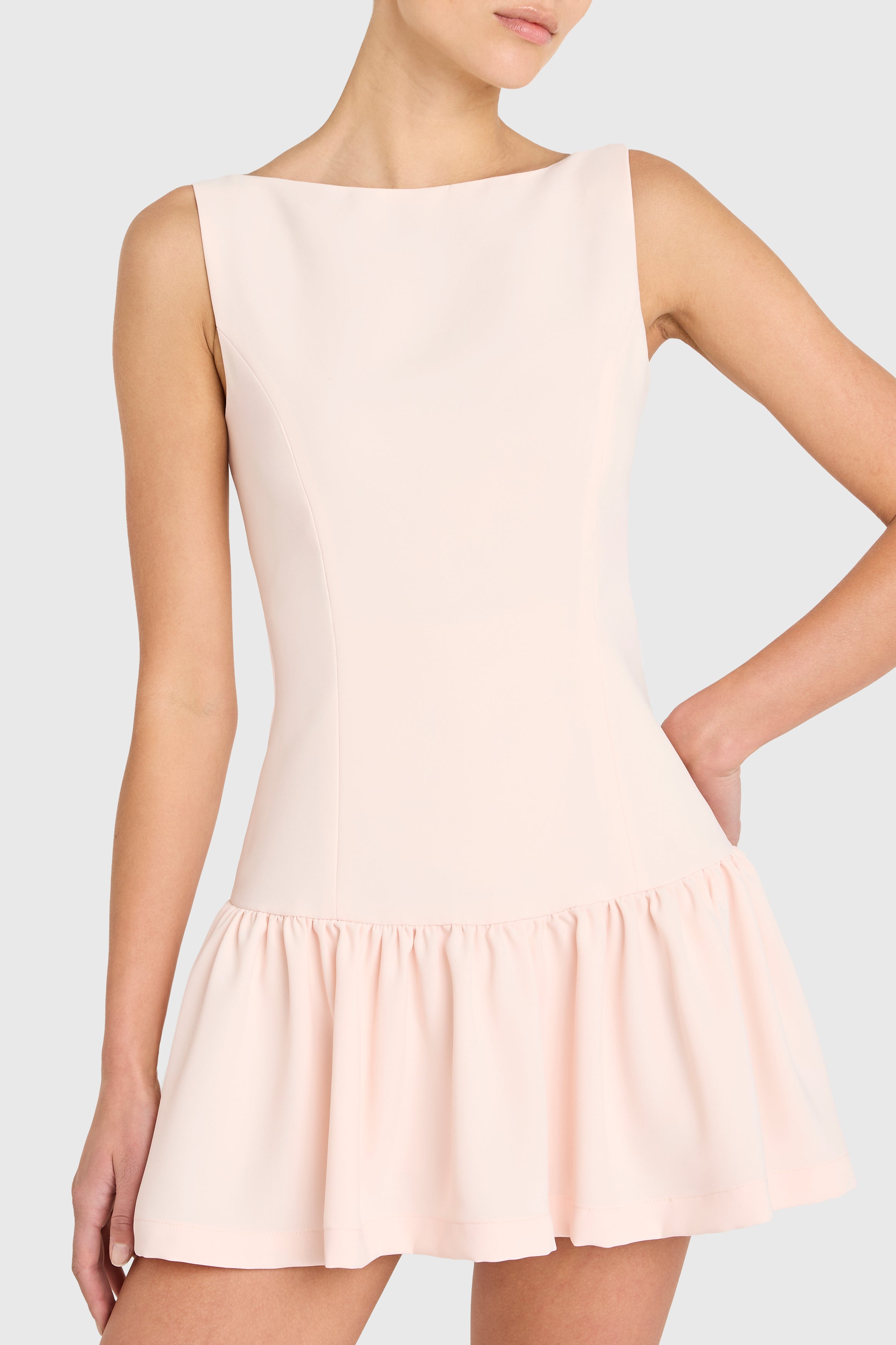 Woman wearing a light pink dress against a plain background