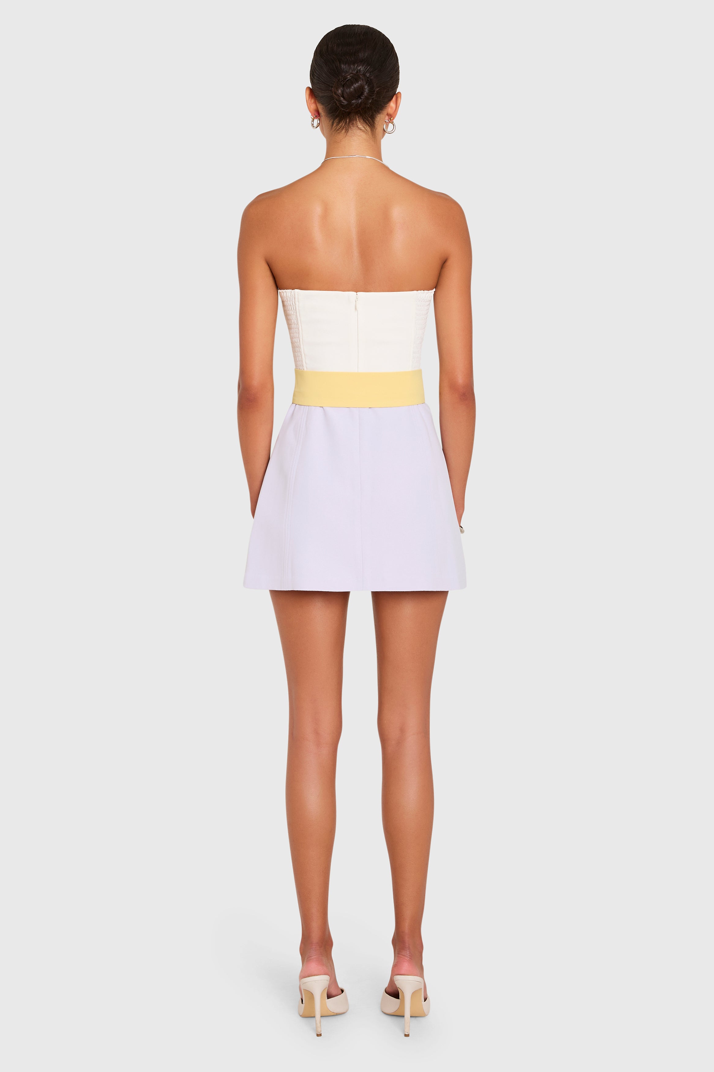 Amanda Uprichard |   Fae Romper in Ivory-Jasmiine-Daffodil. Model wears a color block mini dress against a white backgorund.