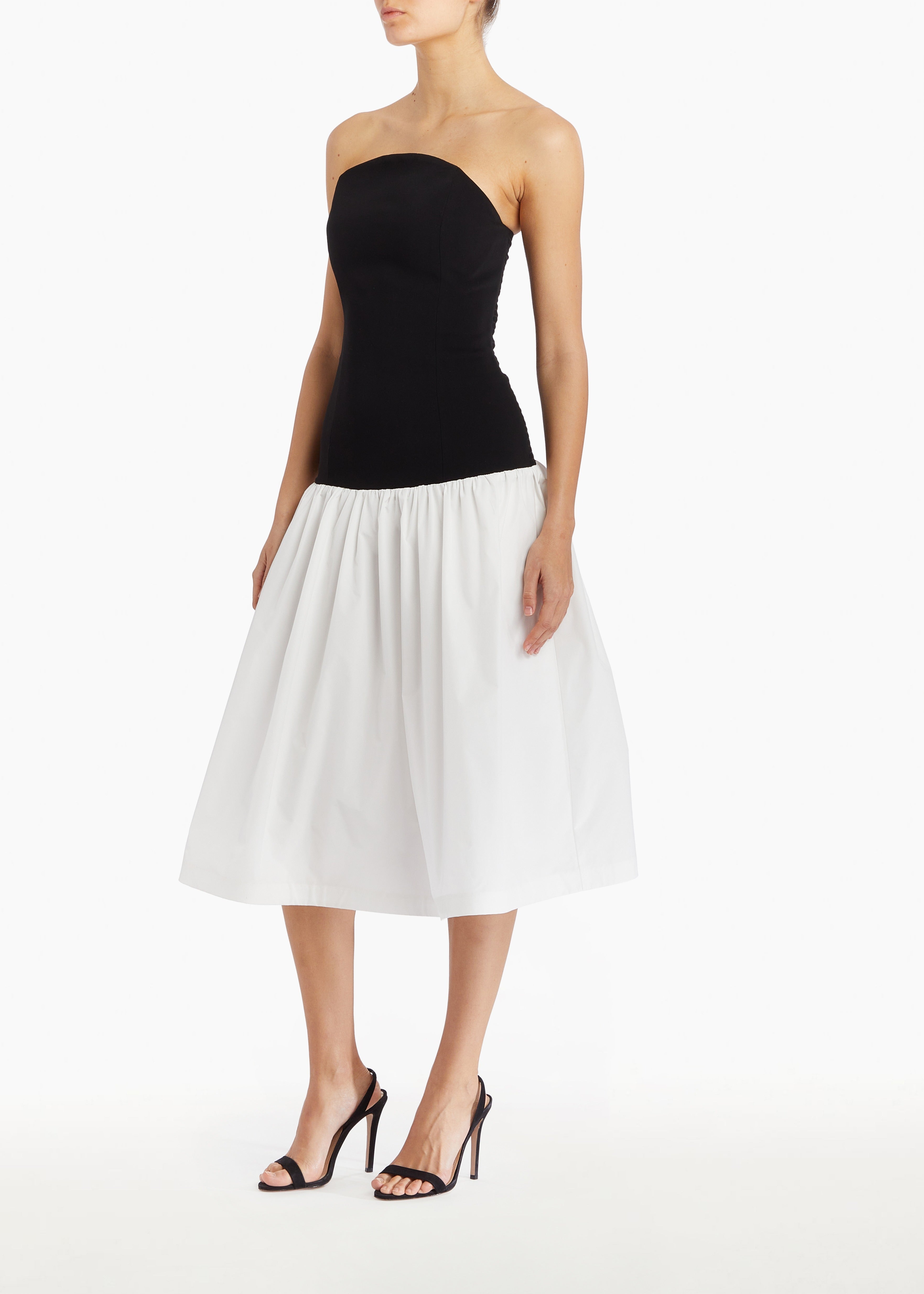 Model wearing a Black and white strapless dress on a white background