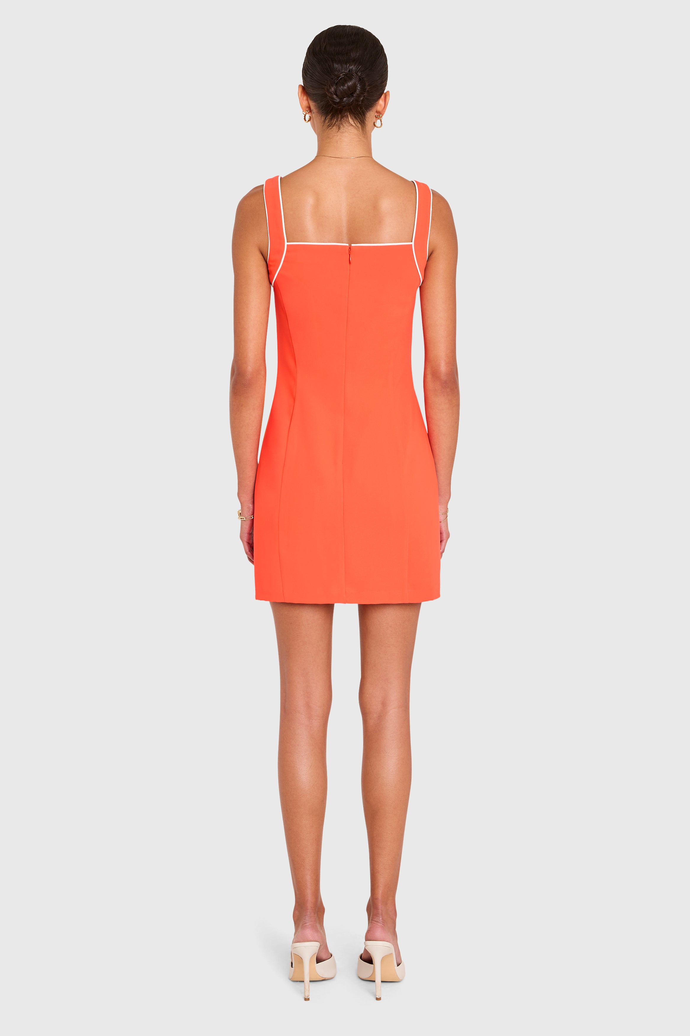 Amanda Uprichard |   Rosie Dress in Serrano. Model wears an orange mini dress against a white backgorund.