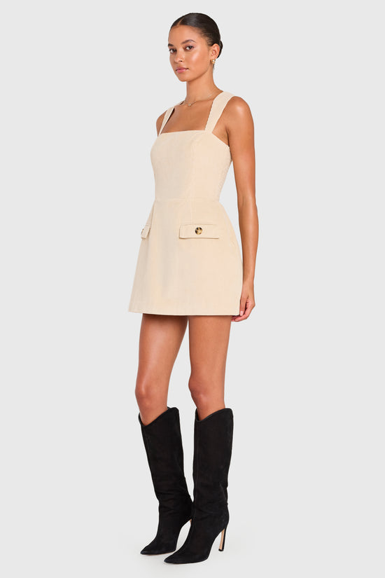 Woman wearing a beige dress with black knee-high boots on a white background view 2