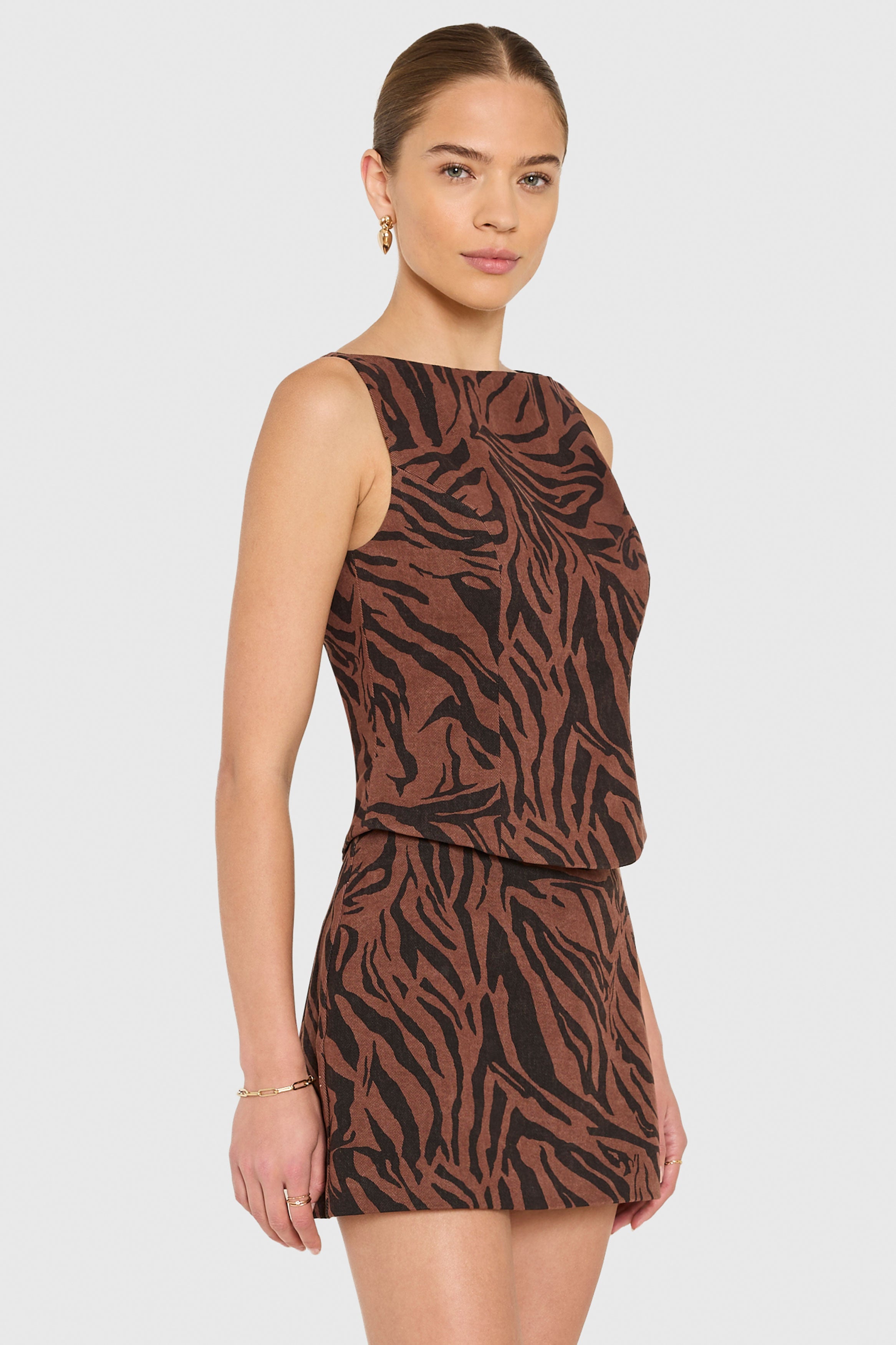 Woman wearing a brown and black zebra print dress on a light gray background