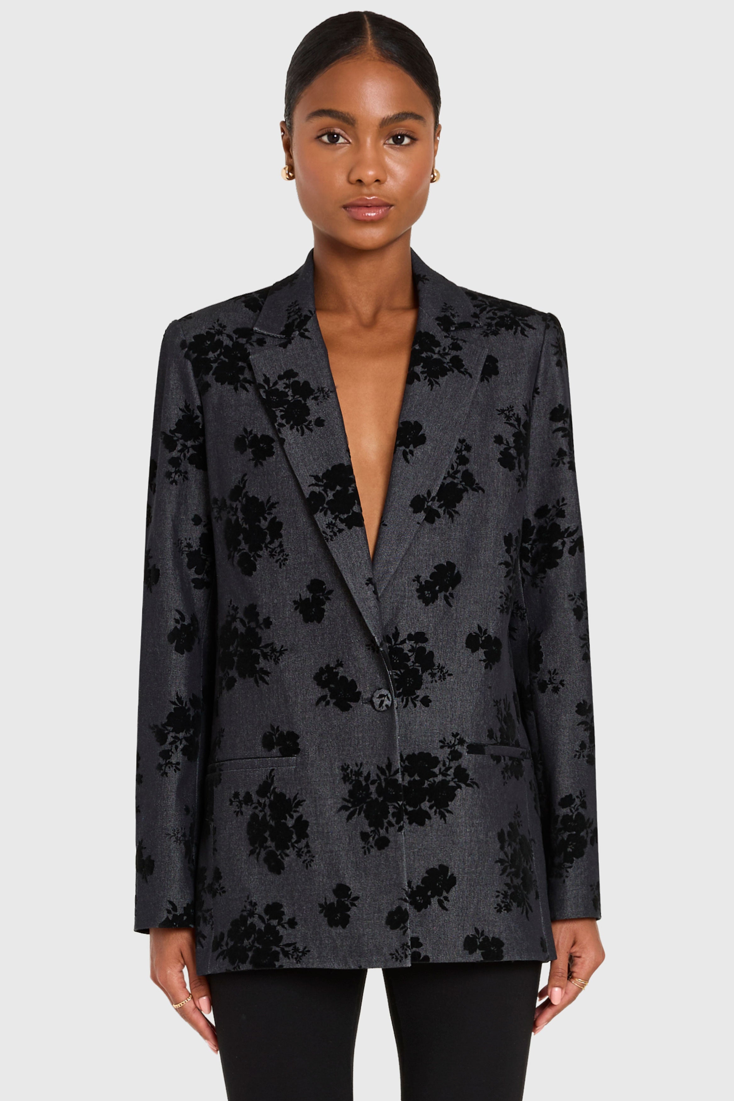 Woman wearing a dark floral blazer on a white background