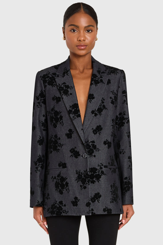 Woman wearing a dark floral blazer on a white background view 1
