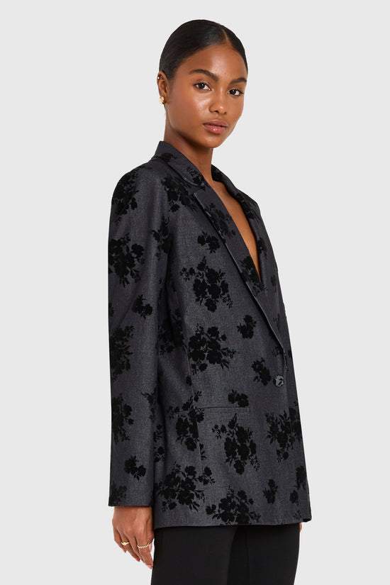 Woman wearing a black floral blazer on a white background view 2