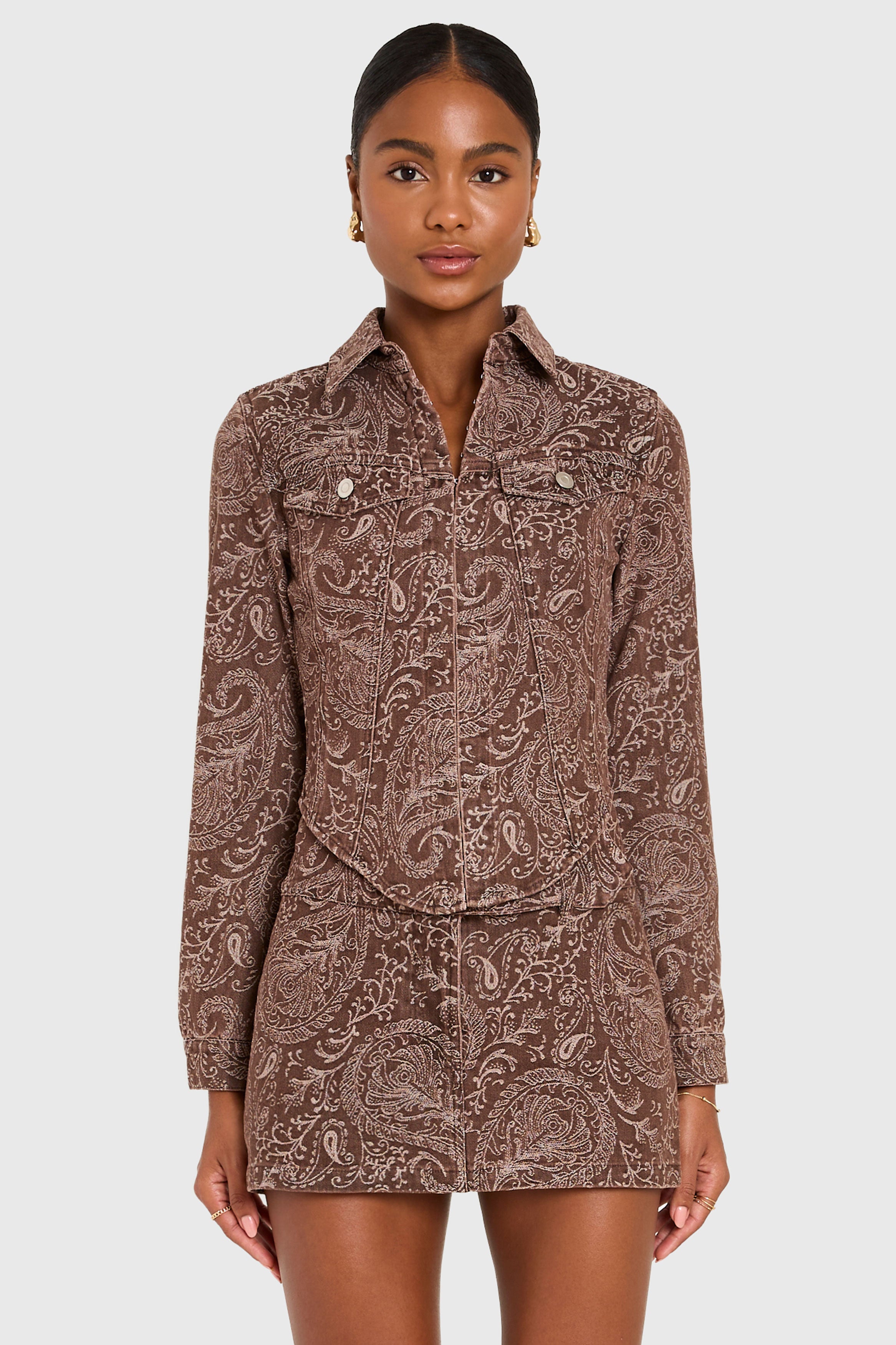 Woman wearing a brown paisley patterned shirt and shorts on a white background