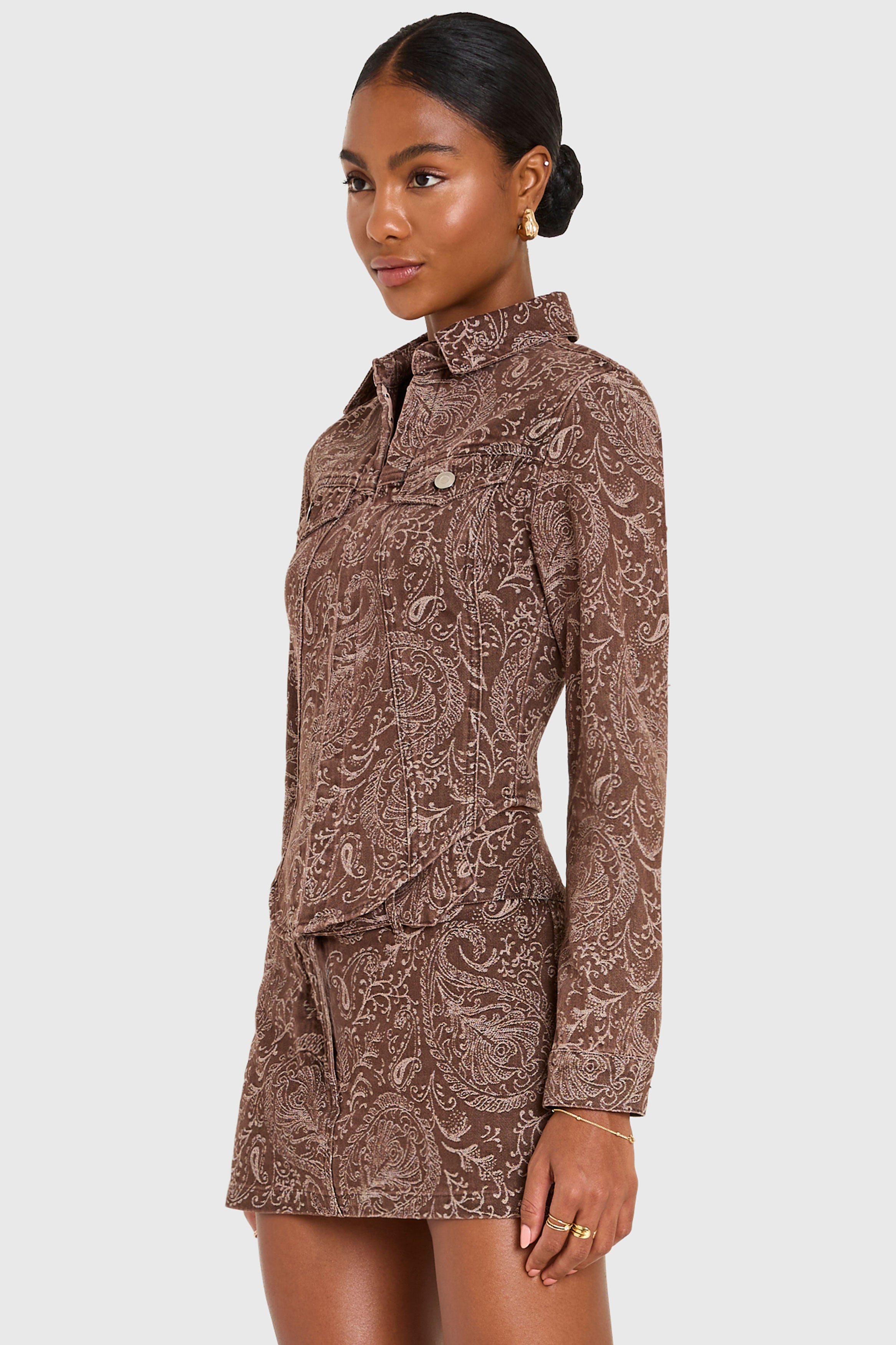 Woman wearing a brown paisley patterned dress on a white background