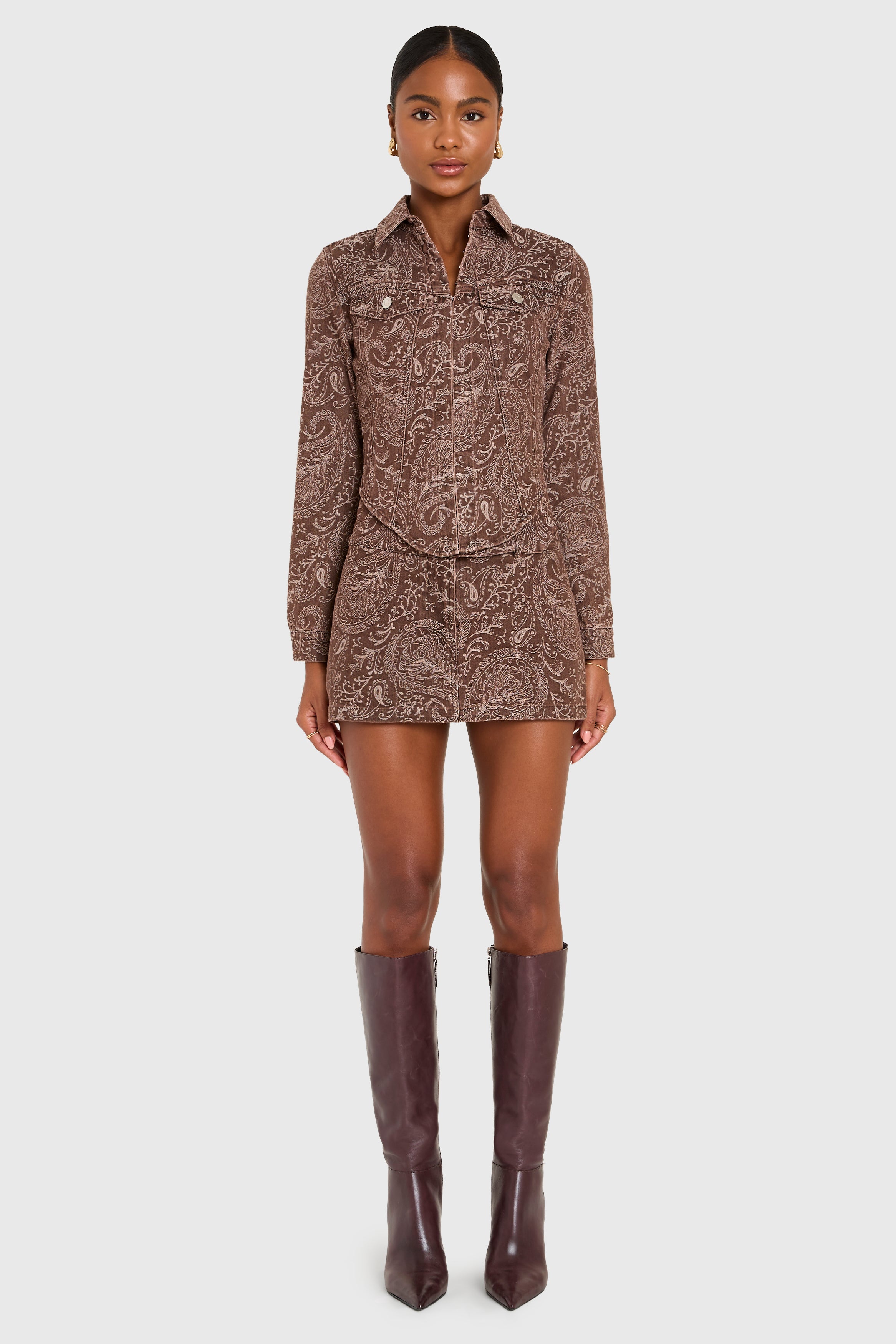 Woman wearing a patterned dress and brown knee-high boots on a white background