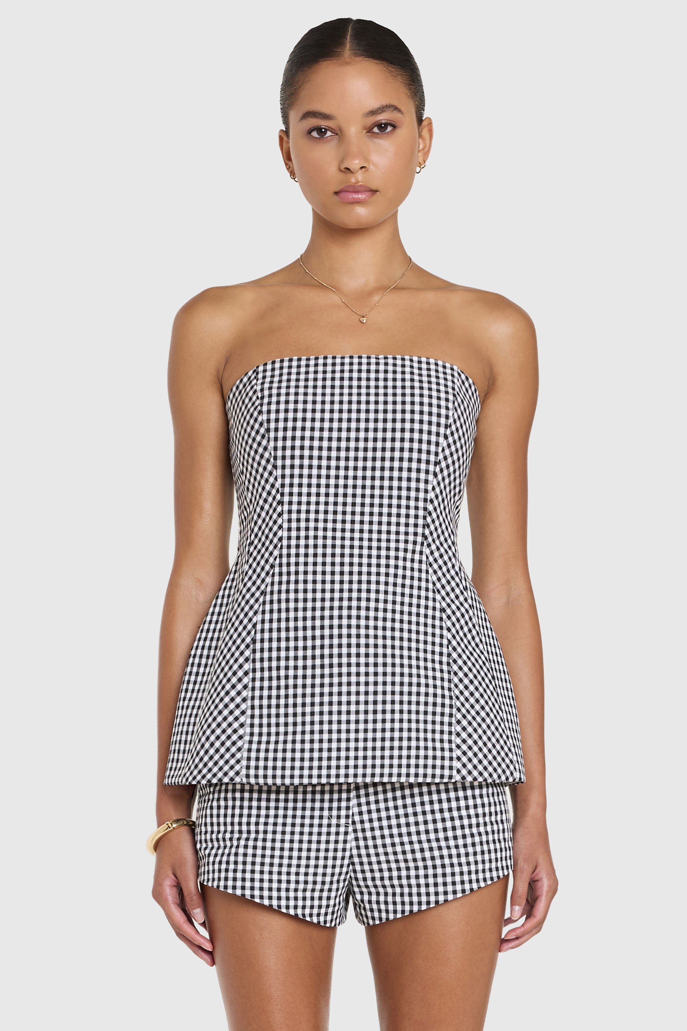 Woman wearing a black and white checkered strapless top and shorts on a light gray background