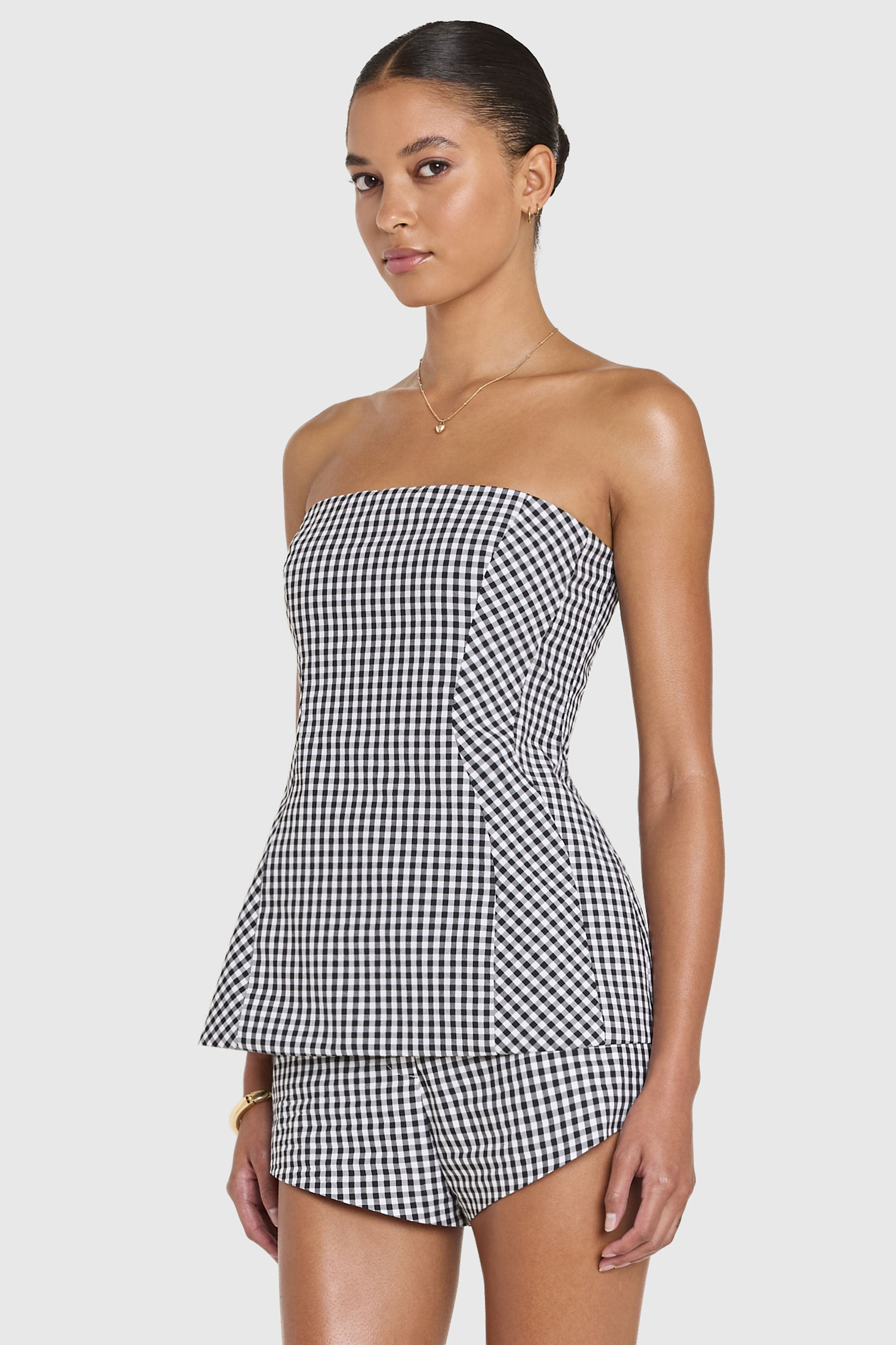 Woman wearing a black and white checkered strapless dress on a plain background