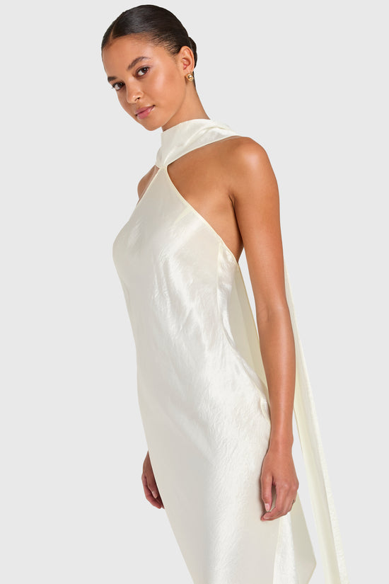 Woman wearing a white halter neck dress against a plain background