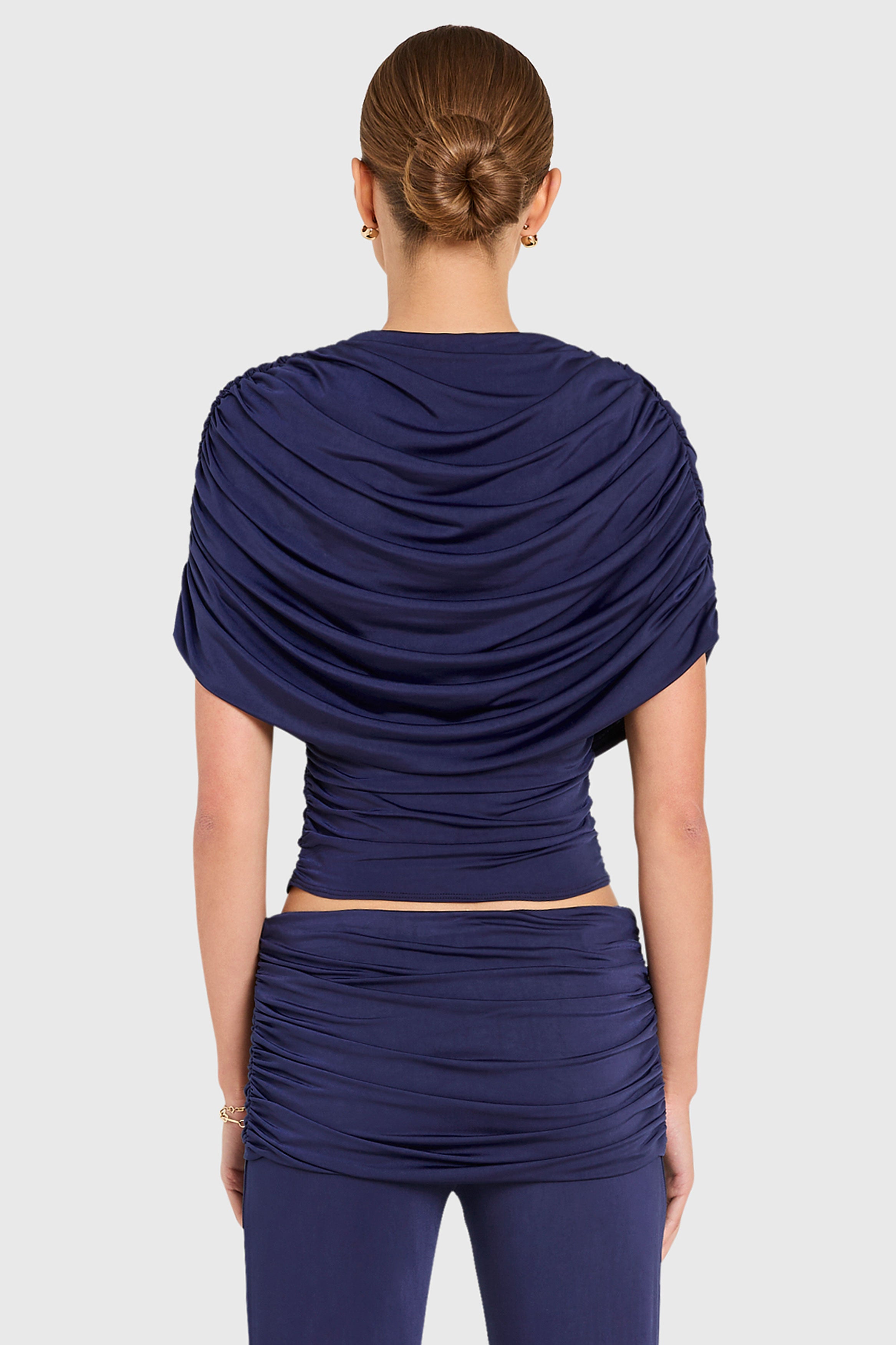 Amanda Uprichard |   Marcelle Top in Navy Blue. Model wears blue top against a white backgorund.