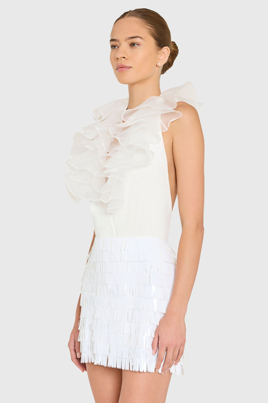 Woman wearing a white dress with ruffled top and pleated skirt on a white background view 2