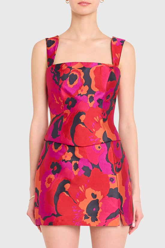 Woman wearing a vibrant floral dress with a plain background view 1