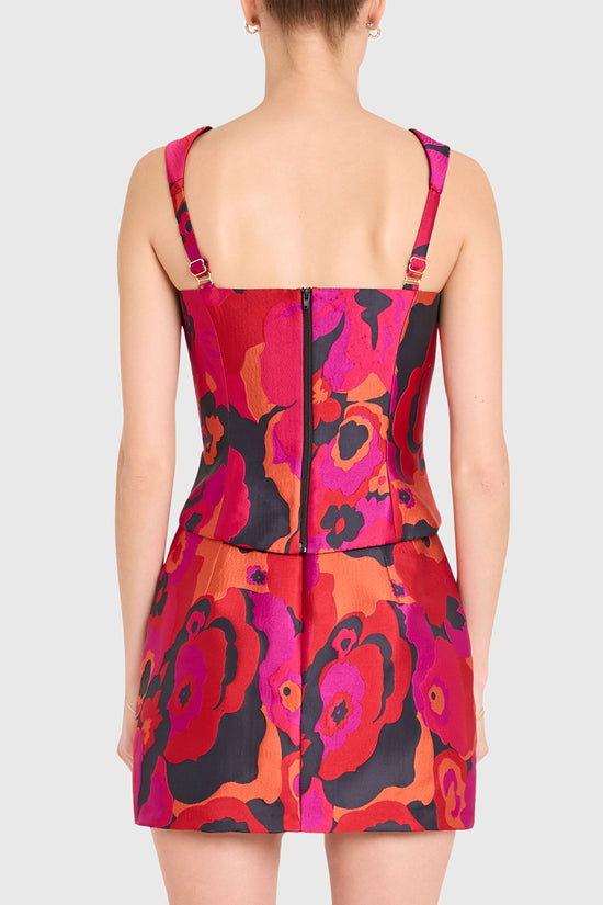 Woman wearing a colorful floral dress with pink straps on a white background