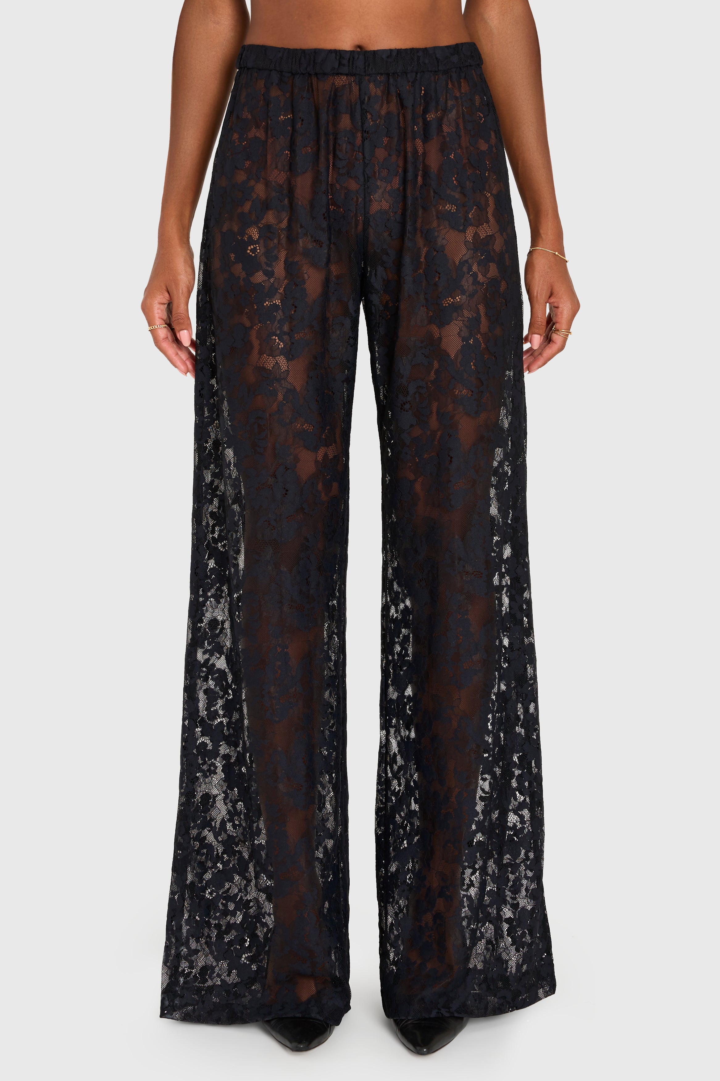 Black lace pants worn by a person on a white background