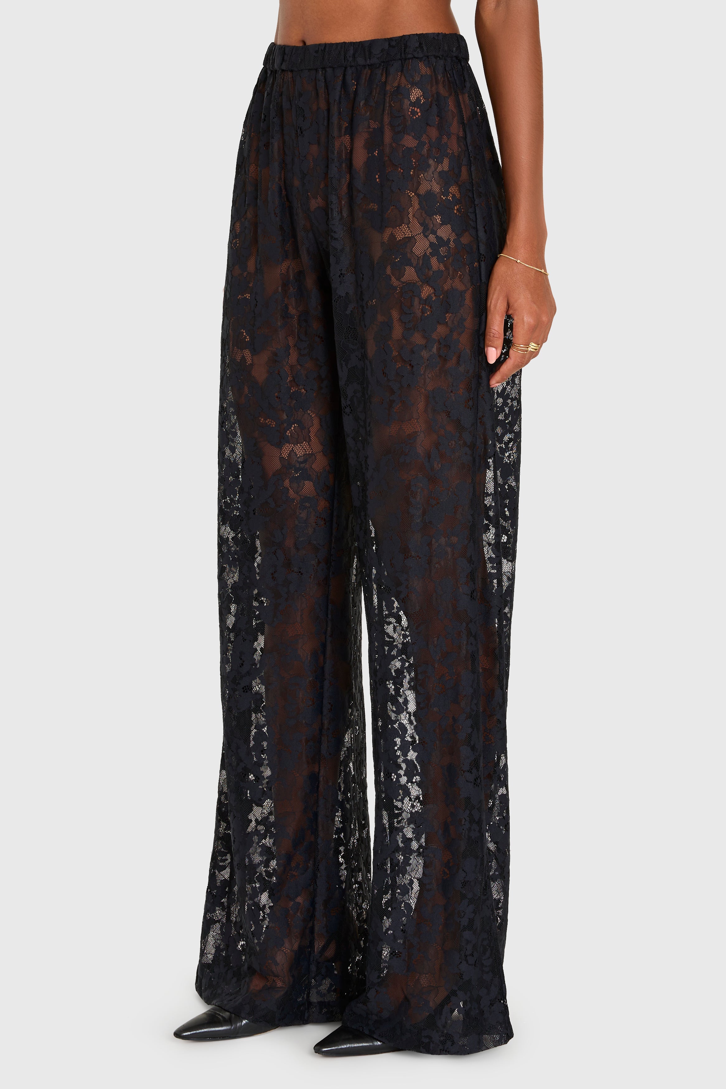 Black lace pants worn by a person on a white background