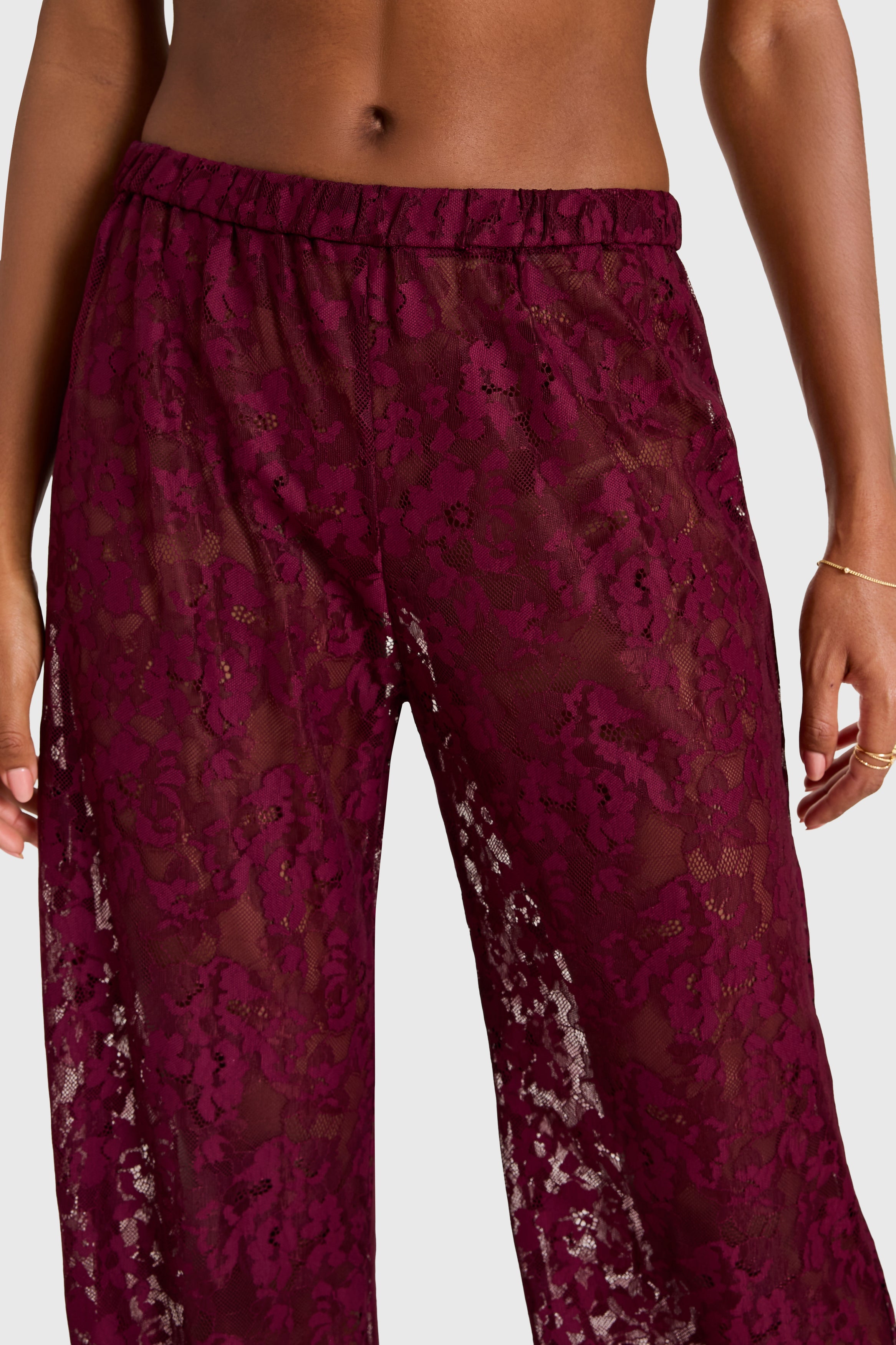 Maroon lace pants on a plain background