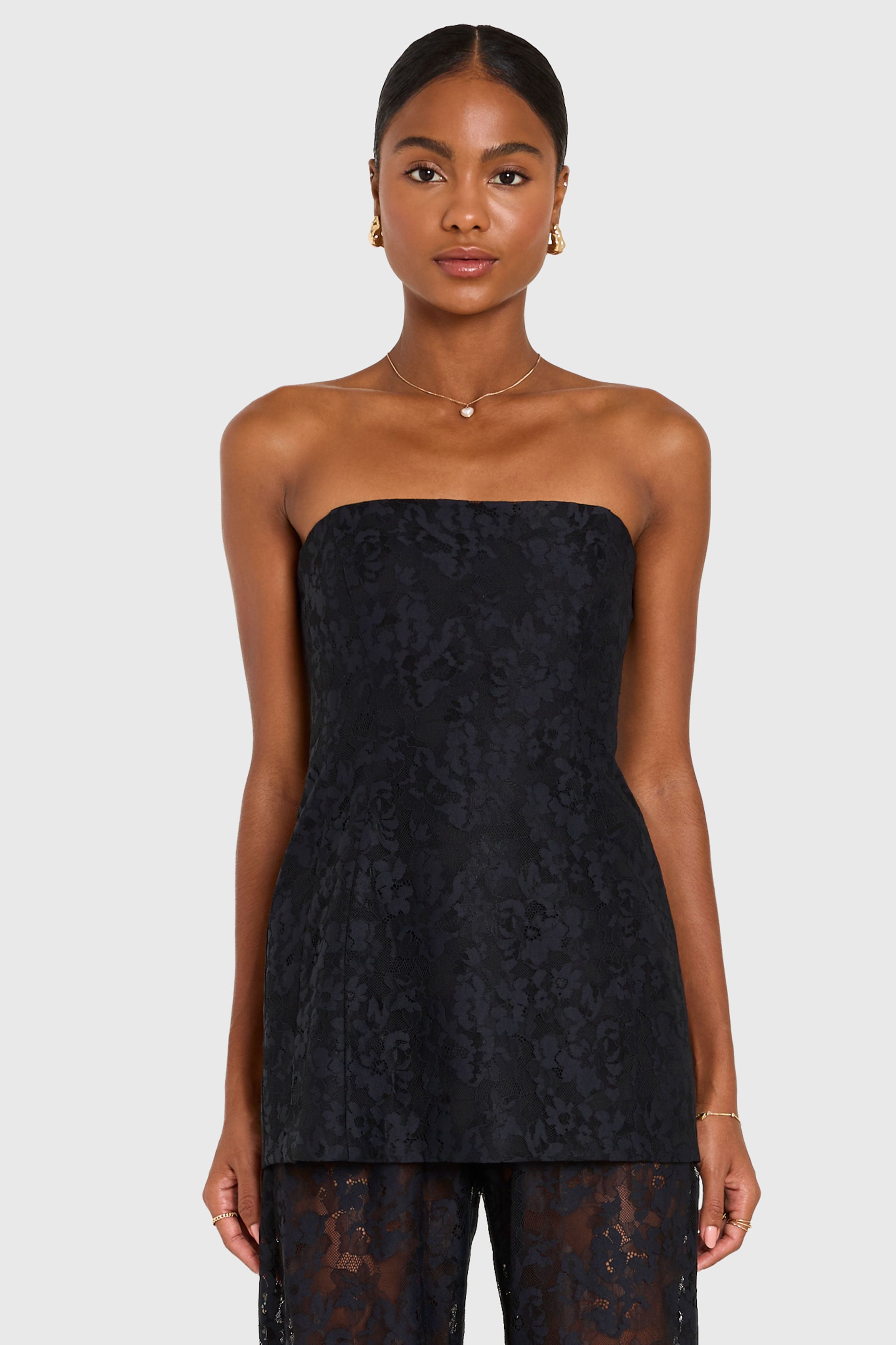 Woman wearing a black strapless lace dress on a white background