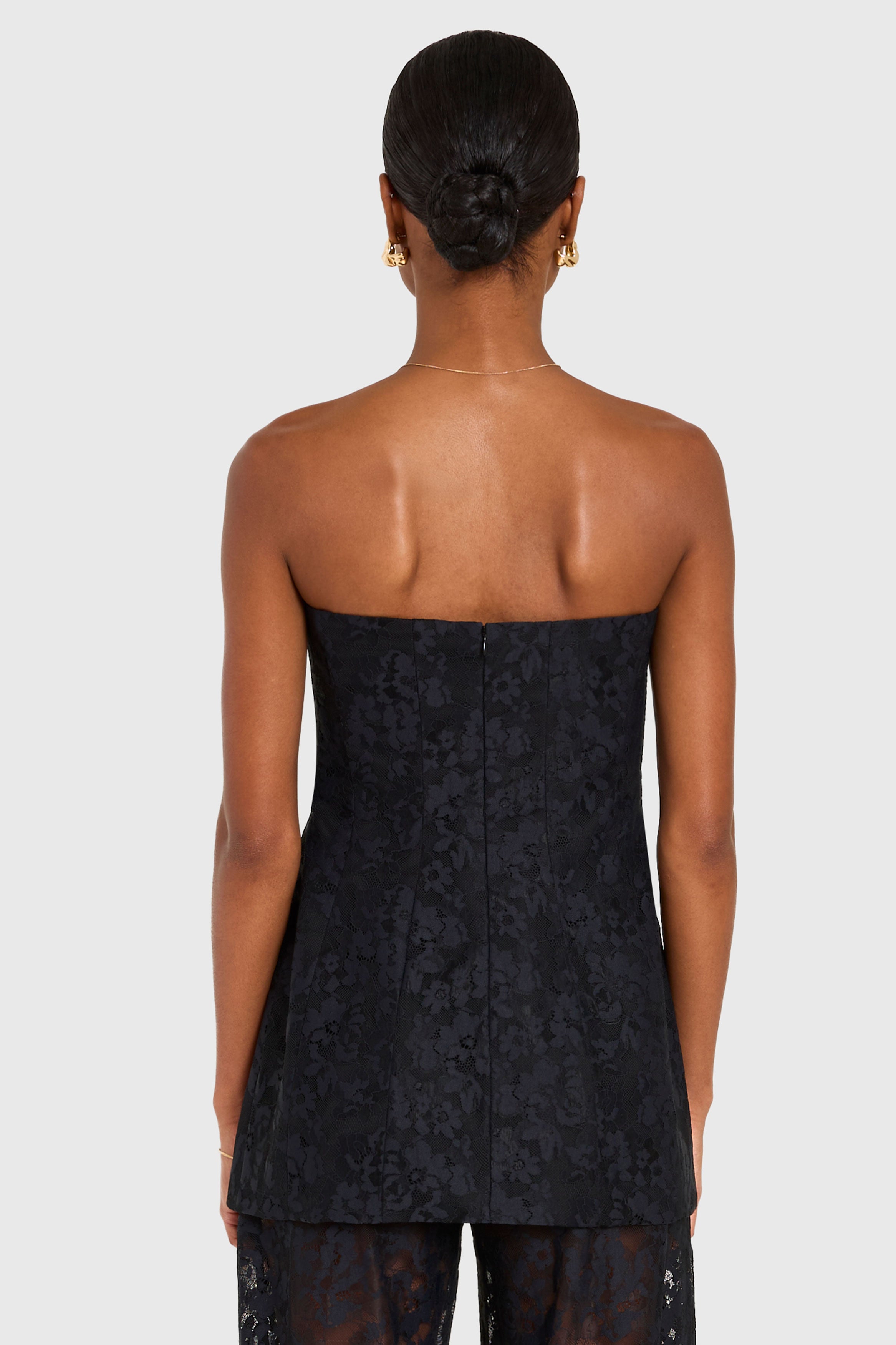 Woman wearing a black strapless dress with floral pattern on a white background