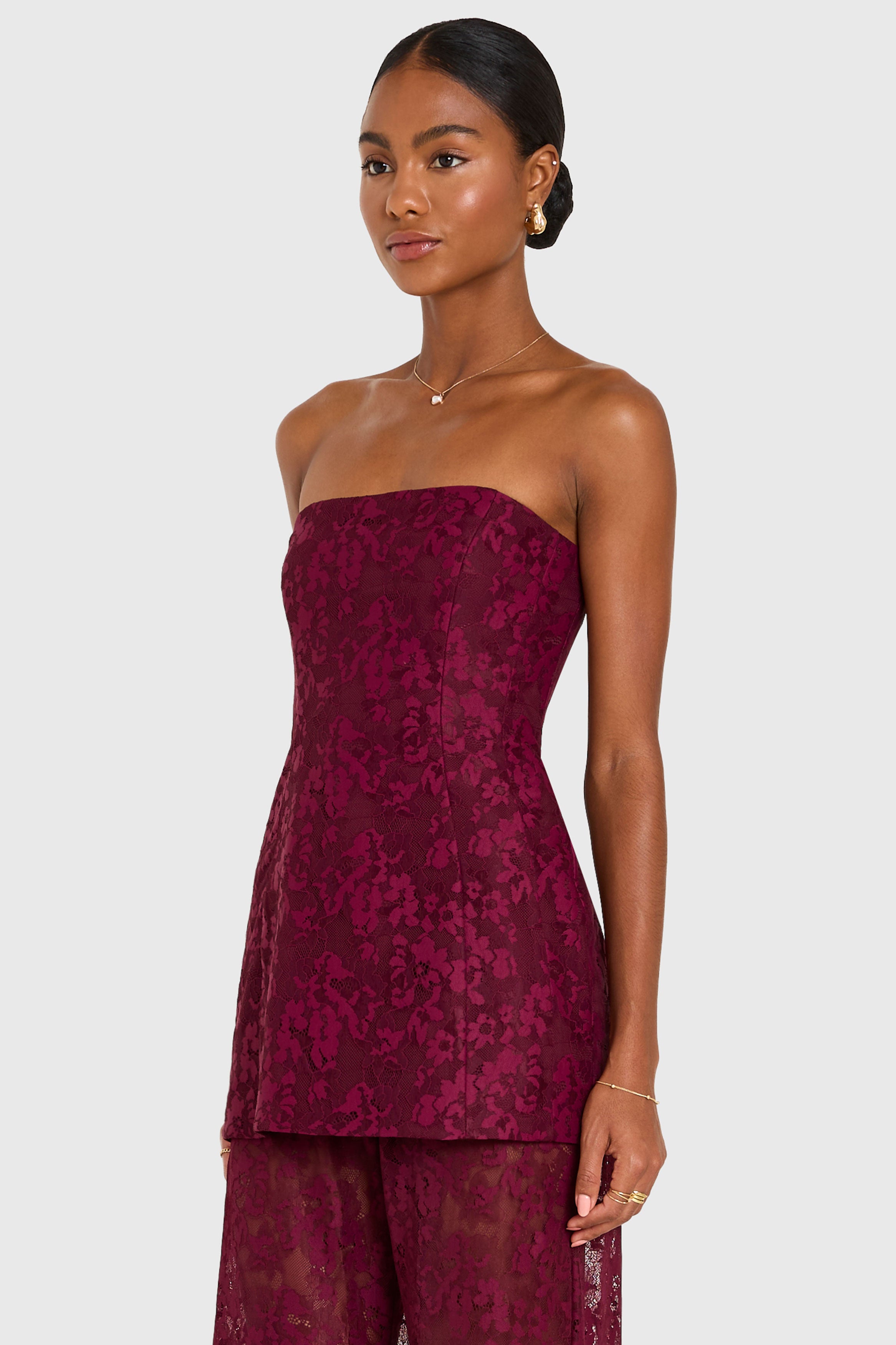 Woman wearing a strapless burgundy dress with floral pattern on a white background