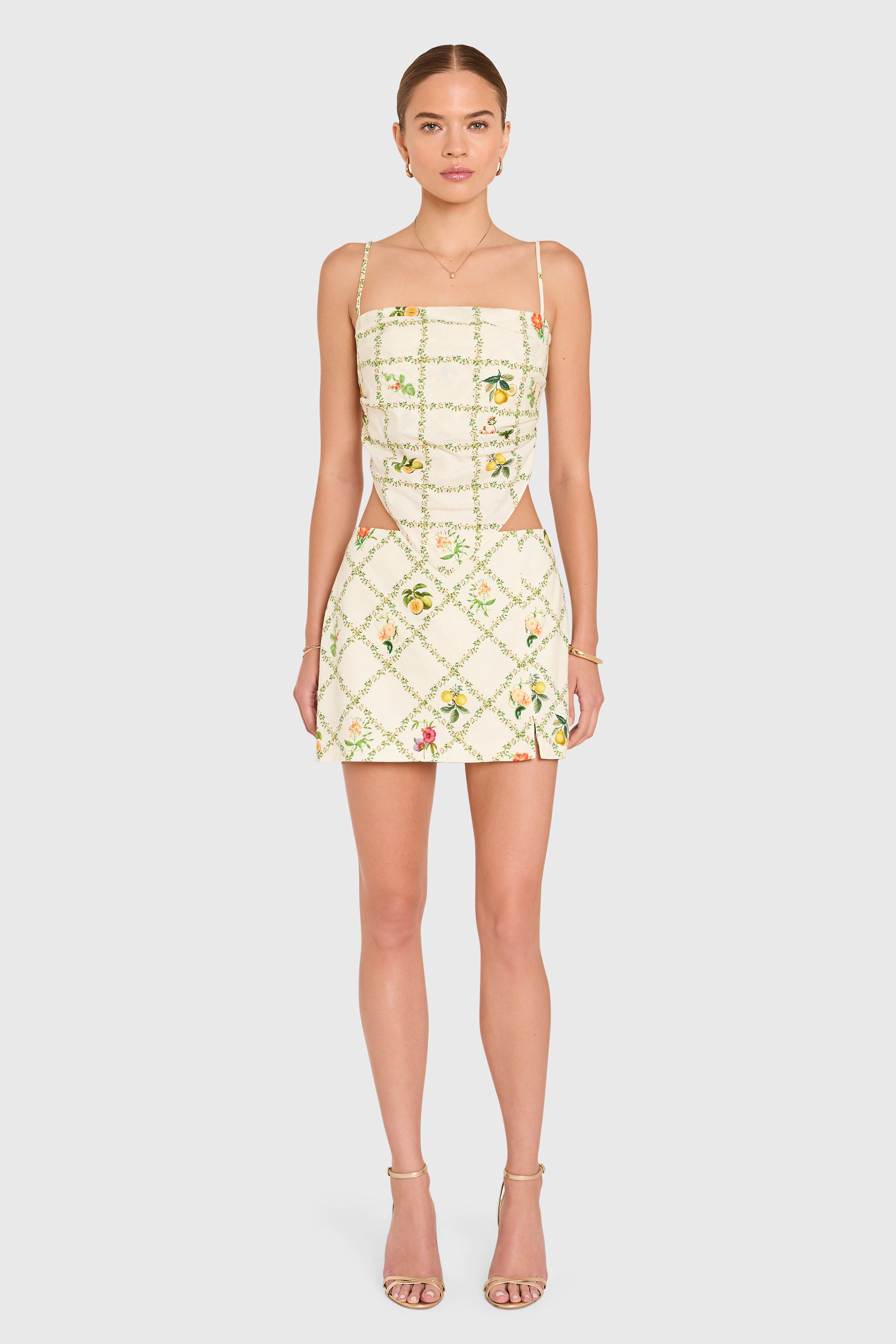 Amanda Uprichard | Juna Top in Trellis. Model wears a mini floral print top against a white backgorund.