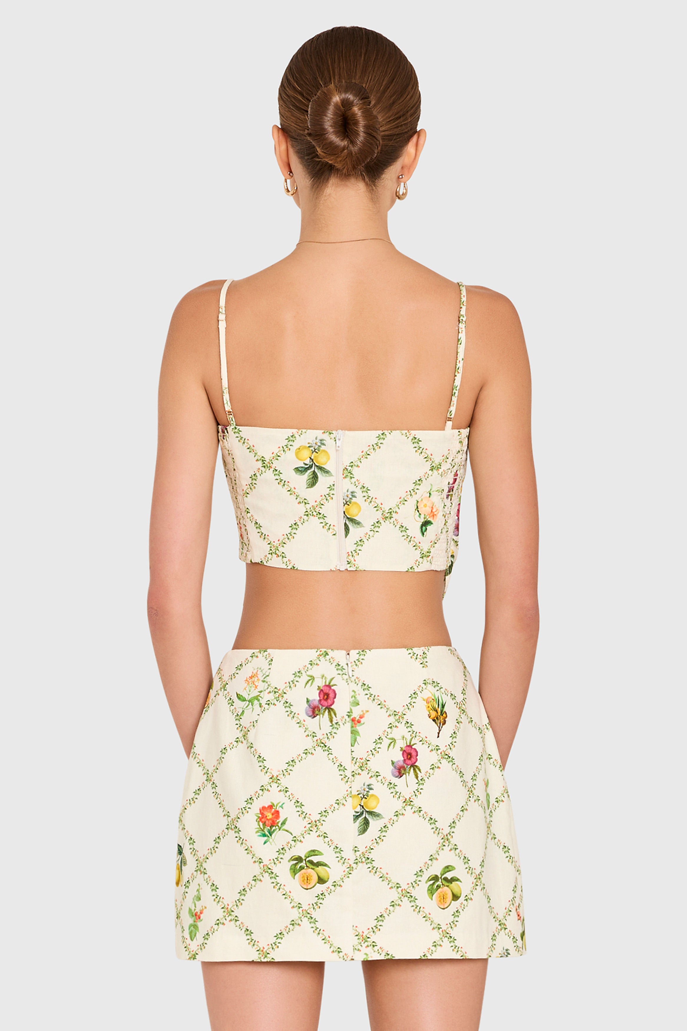 Amanda Uprichard | Juna Top in Trellis. Model wears a mini floral print top against a white backgorund.