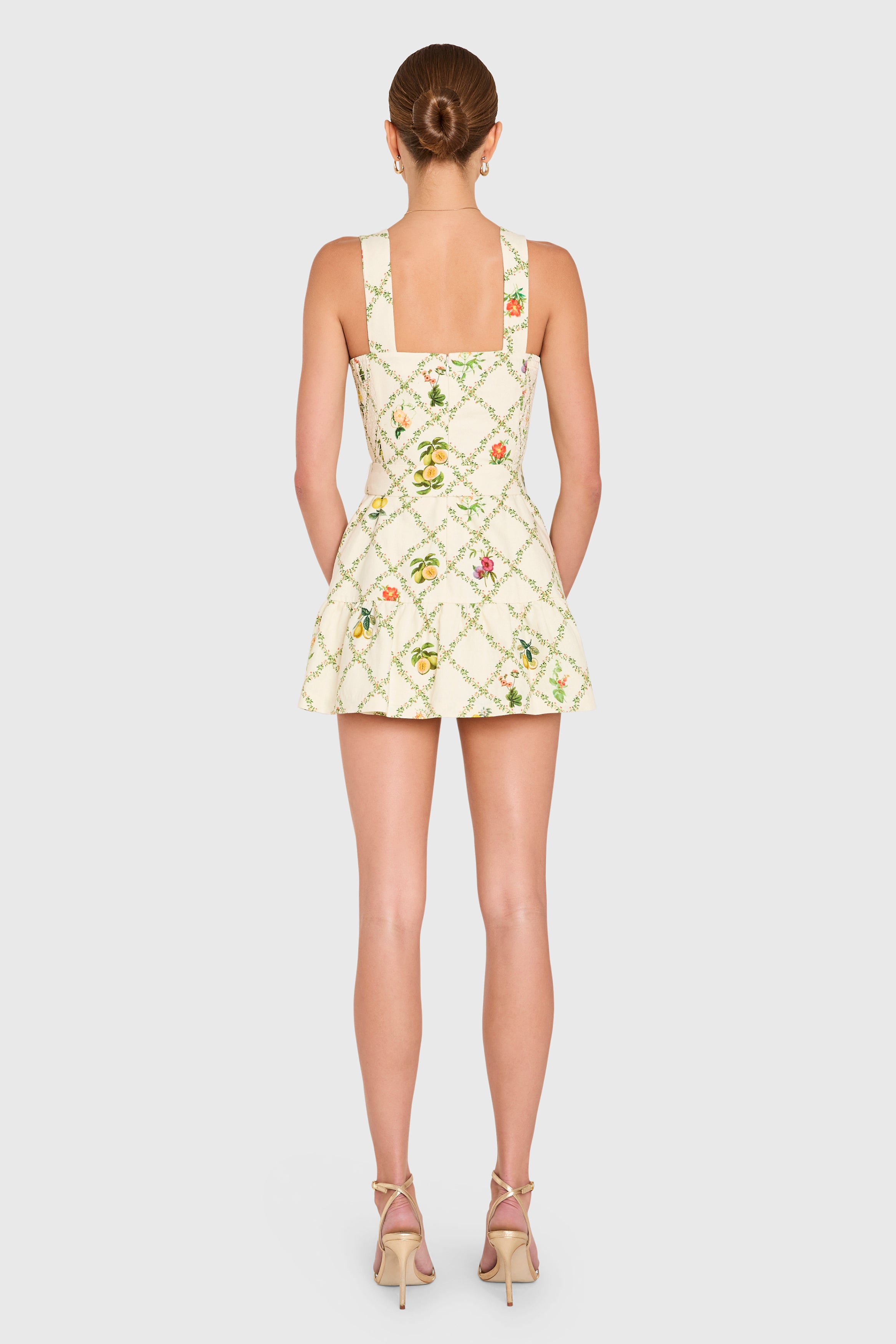 Amanda Uprichard | Lena Romper in Trellis. Model wears a mini skort romper with floral print against a white backgorund.