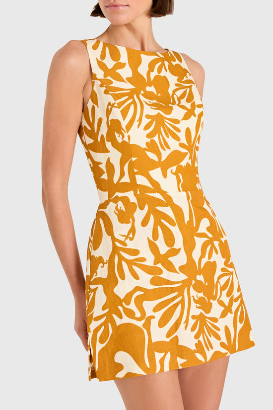 Woman wearing a sleeveless dress with a yellow and white pattern on a plain background