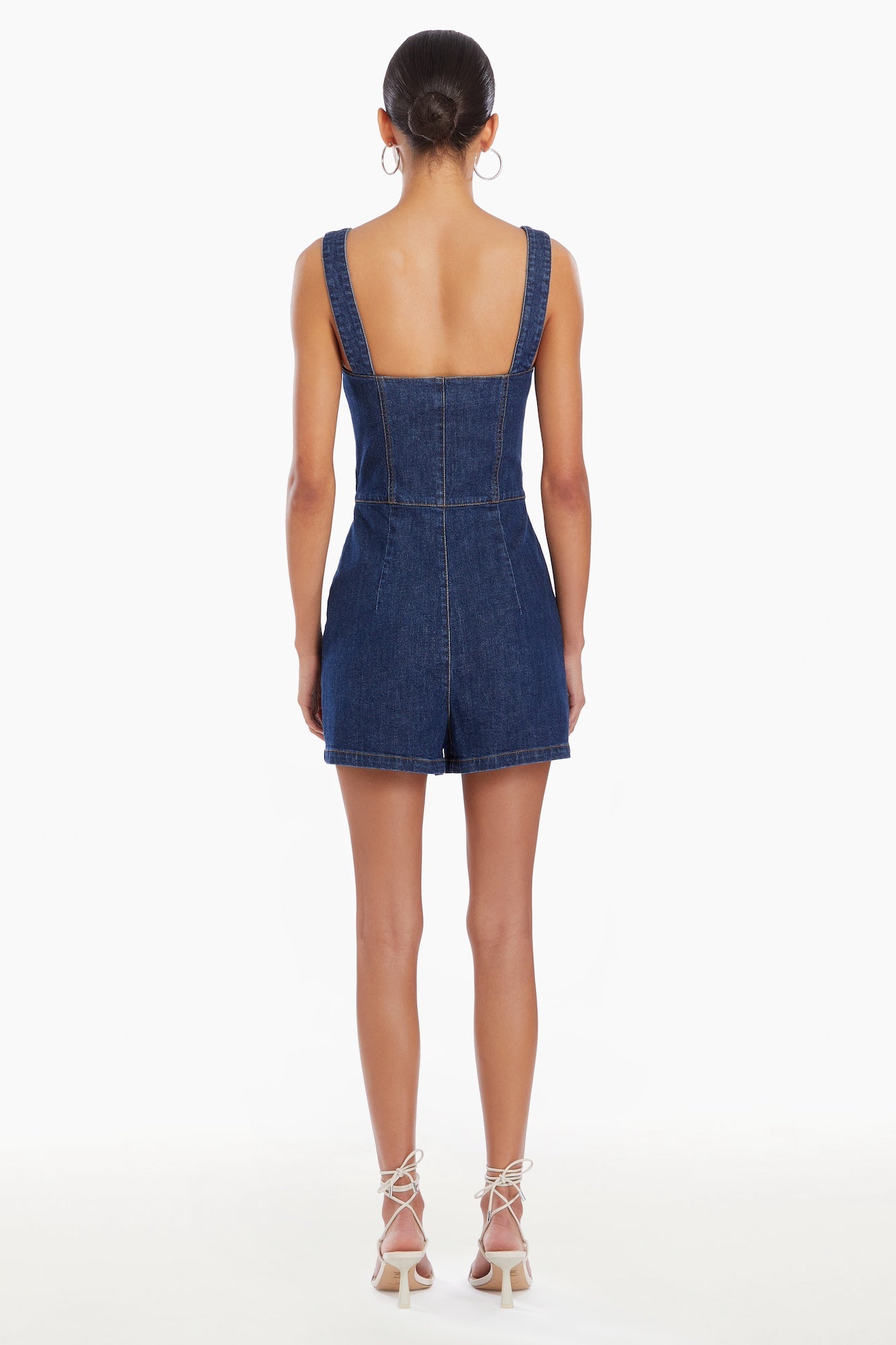 Girl in denim romper, back facing.