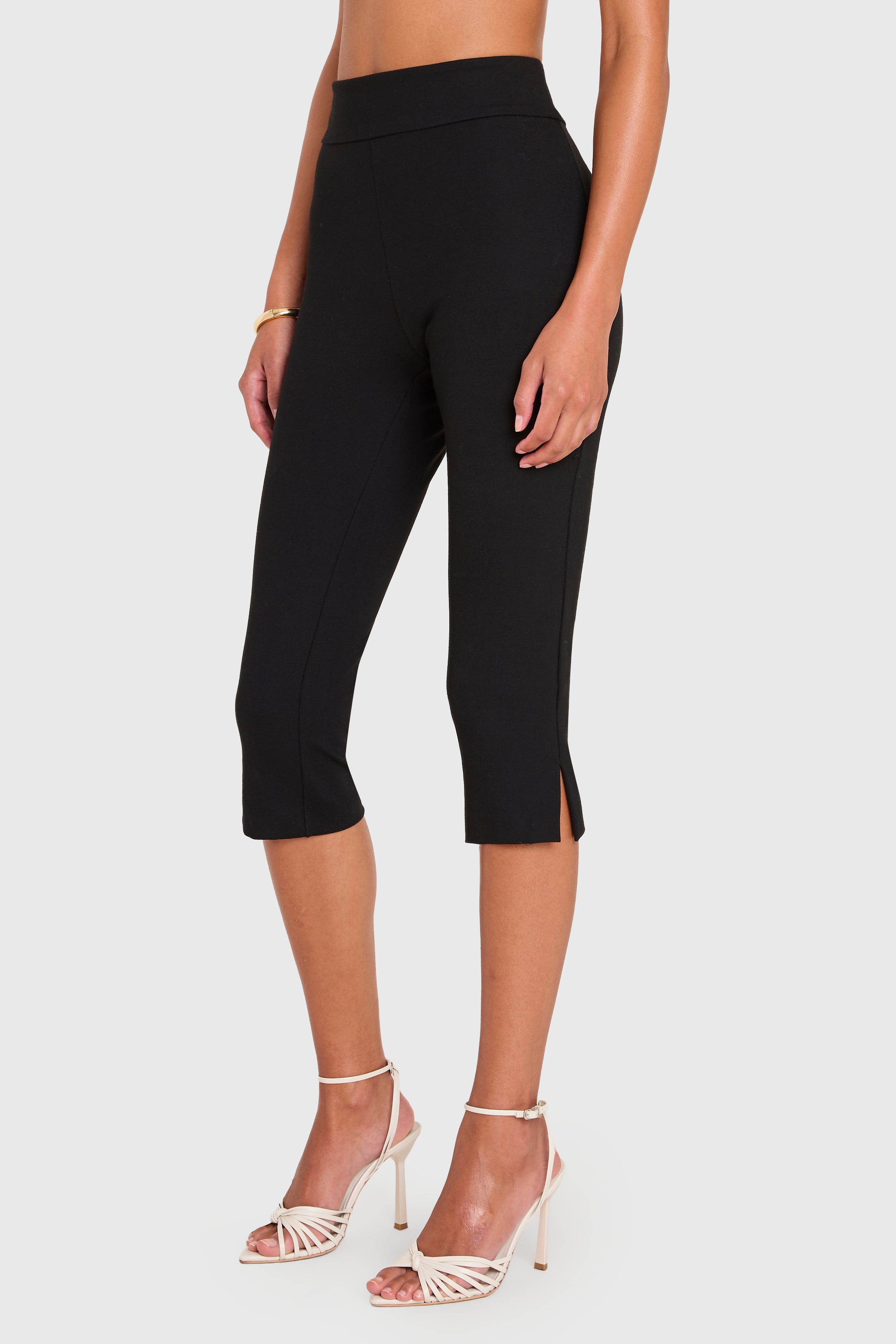 Black capri pants worn by a person on a white background