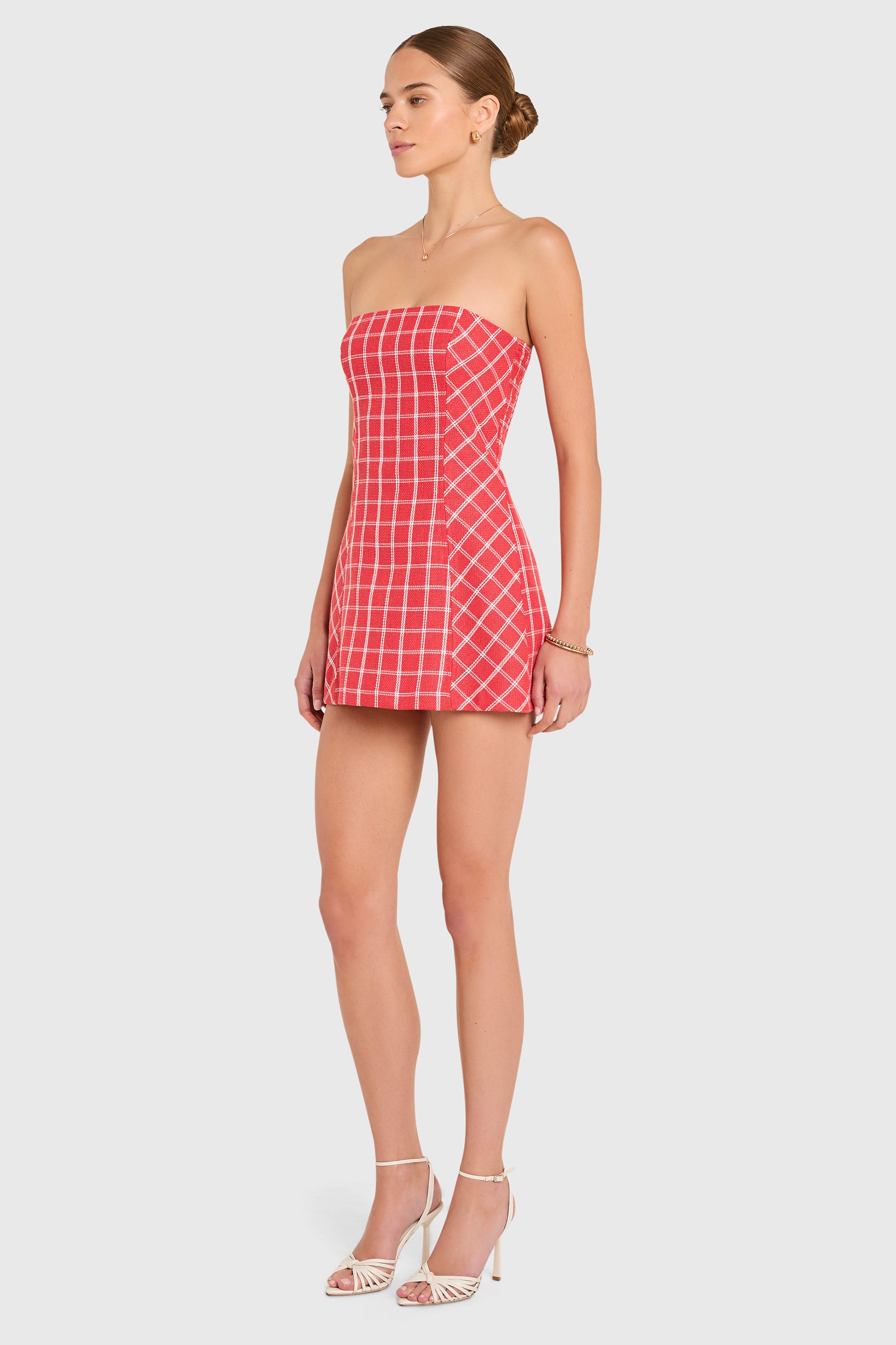 Amanda Uprichard |   Daisy Romper in Mackenzie Plaid. Model wears a red and white plaid strapless mini dress against a white backgorund.