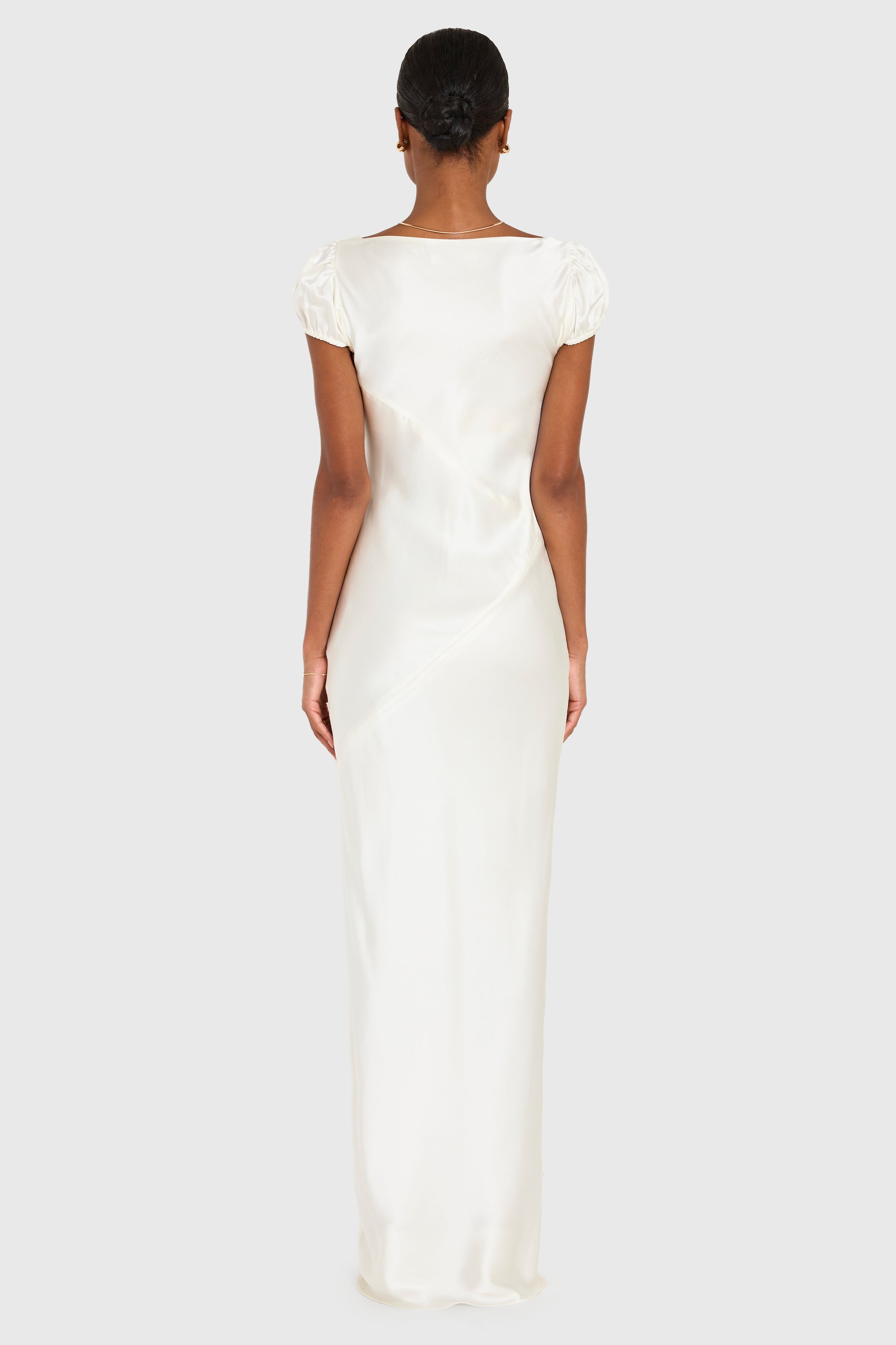 Woman wearing a long white dress on a plain background