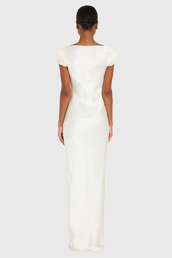 Woman wearing a long white dress on a plain background