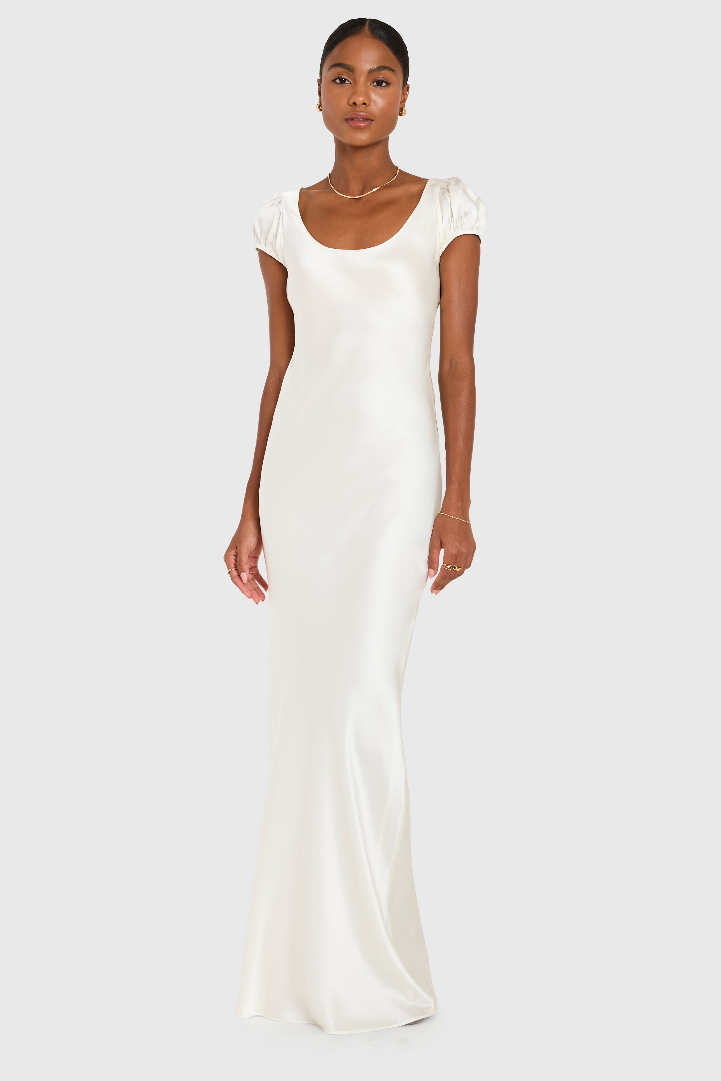 Woman wearing a white satin gown on a plain background