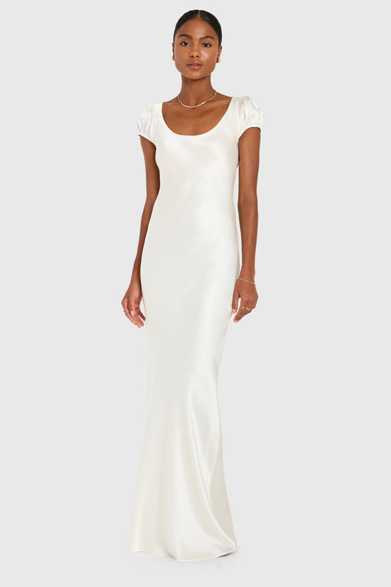 Woman wearing a white satin gown on a plain background